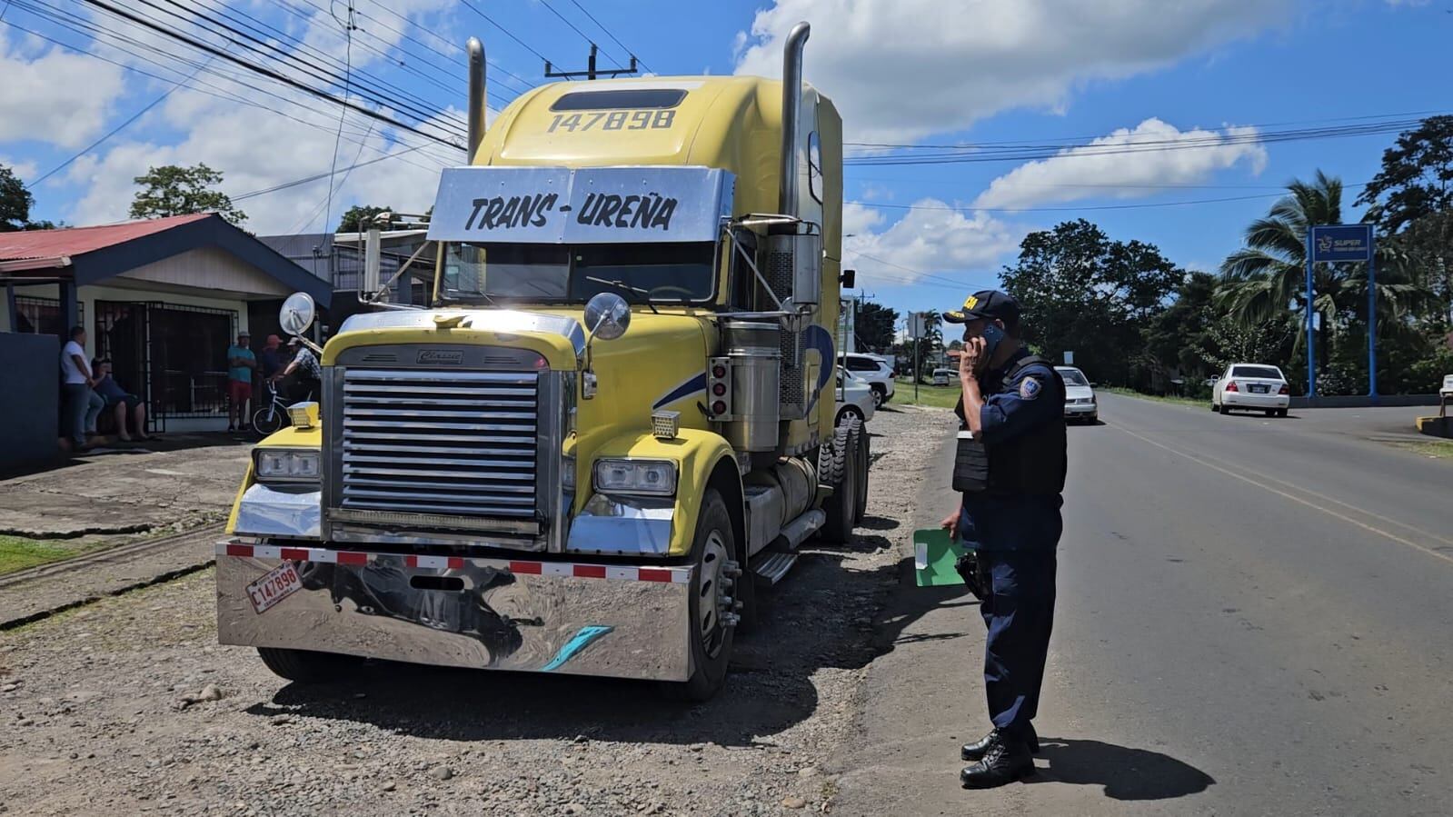 Un camión en la calle y un policía custudiándolo.