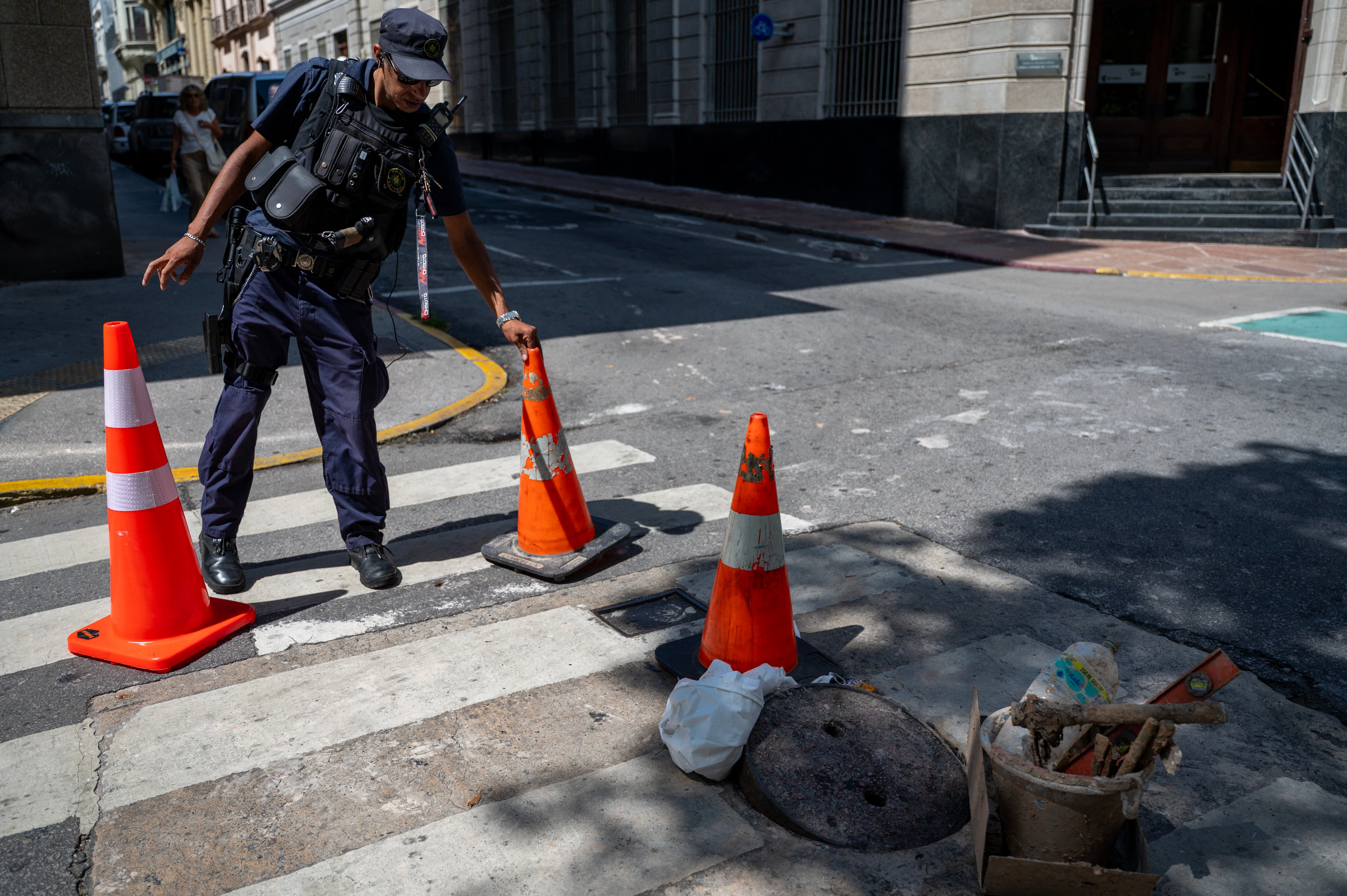 Un policía vigila una alcantarilla un día después de que la policía frustrara un intento de robo a un banco, el 3 de febrero de 2026. La policía uruguaya desmanteló un grupo criminal compuesto por residentes locales, brasileños y paraguayos que excavaron un túnel para acceder al sistema de alcantarillado en el centro histórico de Montevideo con el presunto objetivo de robar un banco, según informó a la AFP una fuente del Ministerio del Interior.