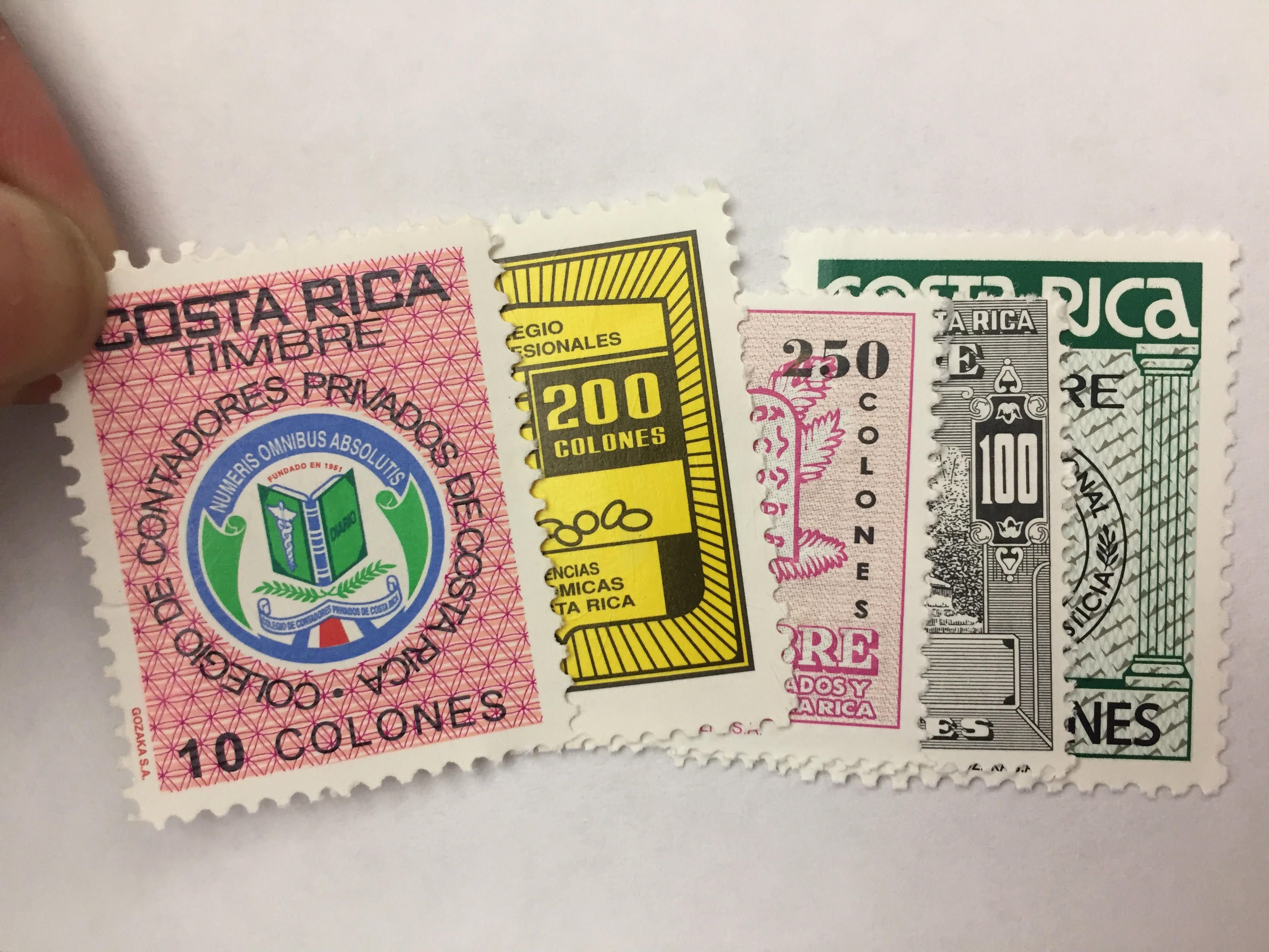 Primer plano de timbres fiscales de Costa Rica en diferentes valores, incluyendo sellos de 10, 200, 250, y 100 colones, sobre un fondo blanco.
