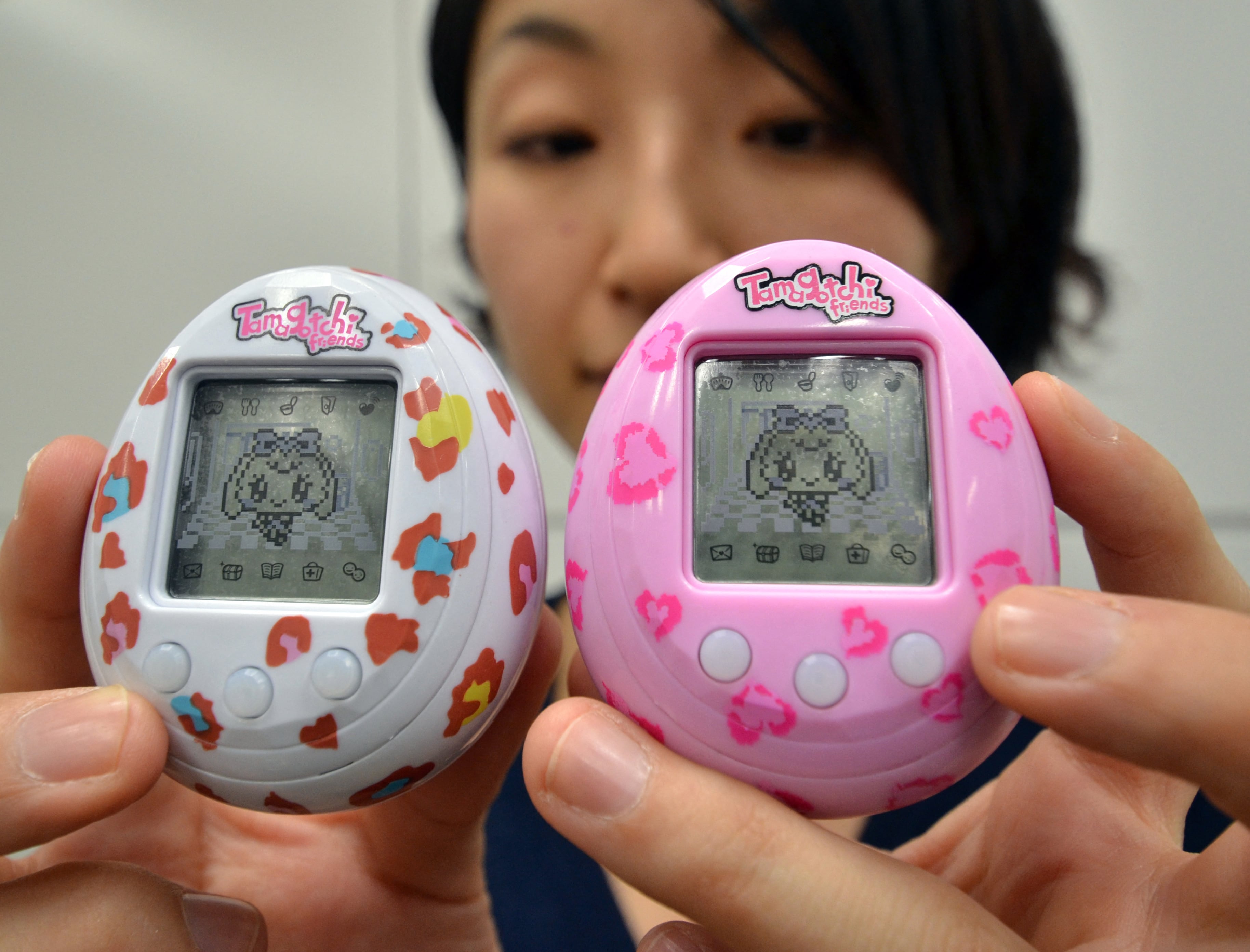 Esta foto, tomada el 27 de noviembre de 2013, muestra a Tomomi Washizu, empleado del gigante japonés de juguetes Bandai, mostrando el nuevo juguete de mascota virtual Tamagotchi, "Tamagotchi Friends", un juguete portátil con forma de huevo y personajes de dibujos animados, en la sede de la compañía en Tokio. Tamagotchi, la mascota virtual con forma de huevo, tan querida por los escolares en los años 90, regresa con fuerza y llegará a las tiendas europeas a tiempo para Navidad.