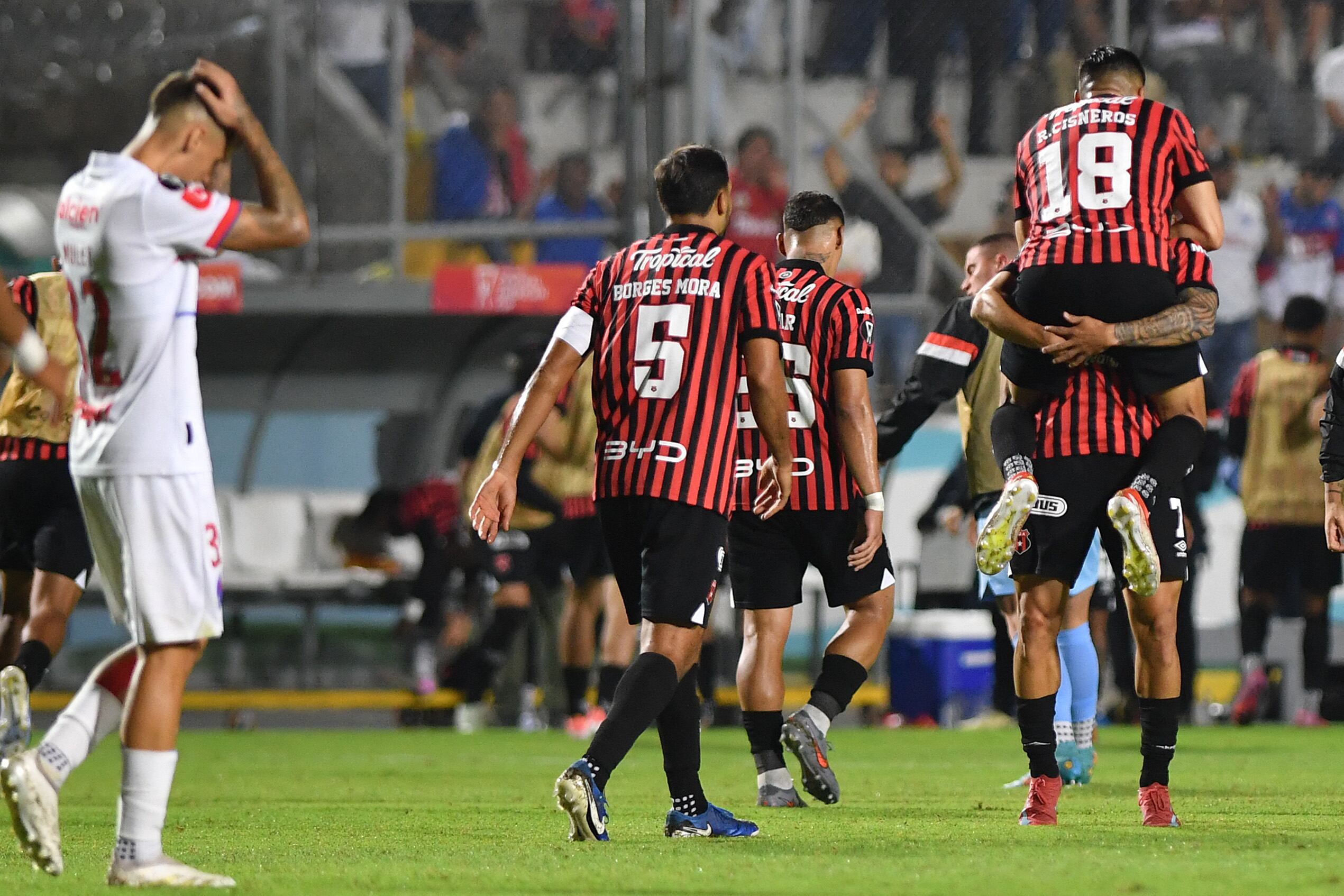 Alajuelense's forward #07 Anthony Hernandez (Bottom-R) celebrates with teammate Mexican forward #18 Ronaldo Cisneros scoring his team's first goal during the second leg of the CONCACAF Central American Cup semifinal football match between Honduras's Olimpia and Costa Rica's Alajuelense at the National Stadium Jose de la Paz Herrera in Tegucigalpa on October 30, 2025. (Photo by Orlando SIERRA / AFP)