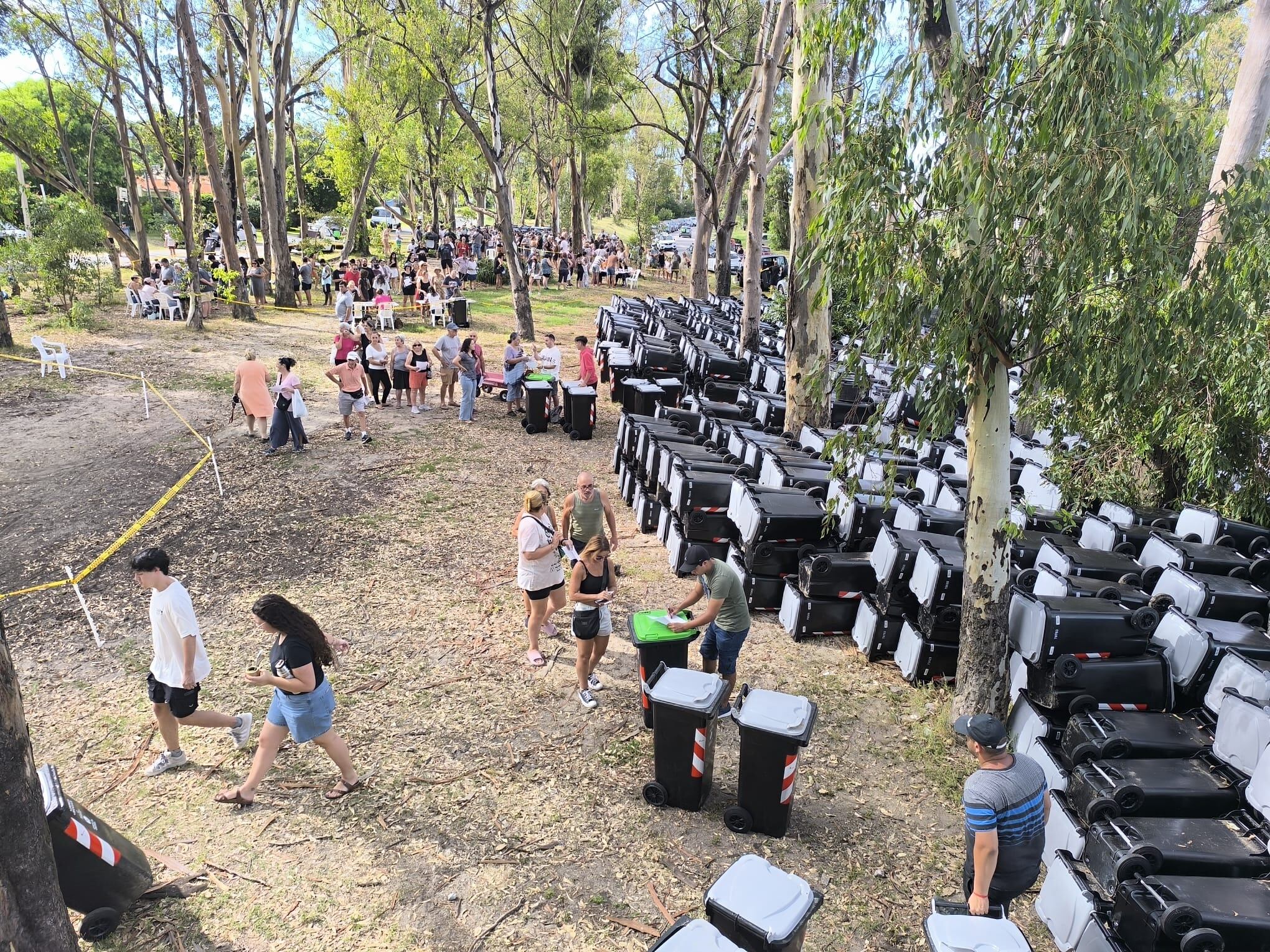 Un grupo de personas en un parque reciben basureros.