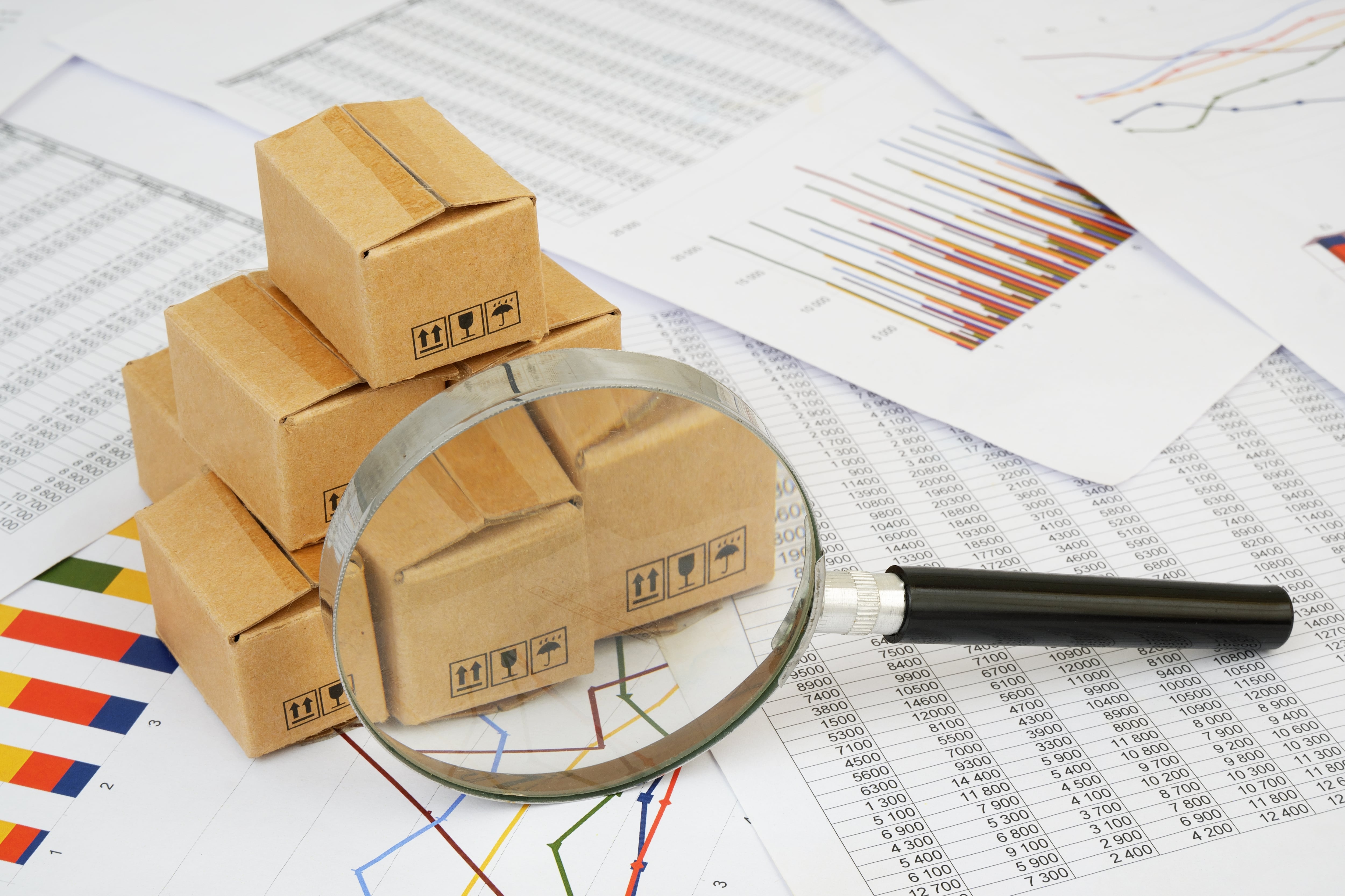 Cajas de exportación sobre gráficos financieros y una lupa, representación de las exportaciones de Costa Rica a Estados Unidos afectadas por el arancel del 10%, con impacto en dispositivos médicos, textiles, piña, banano y café en 2025.