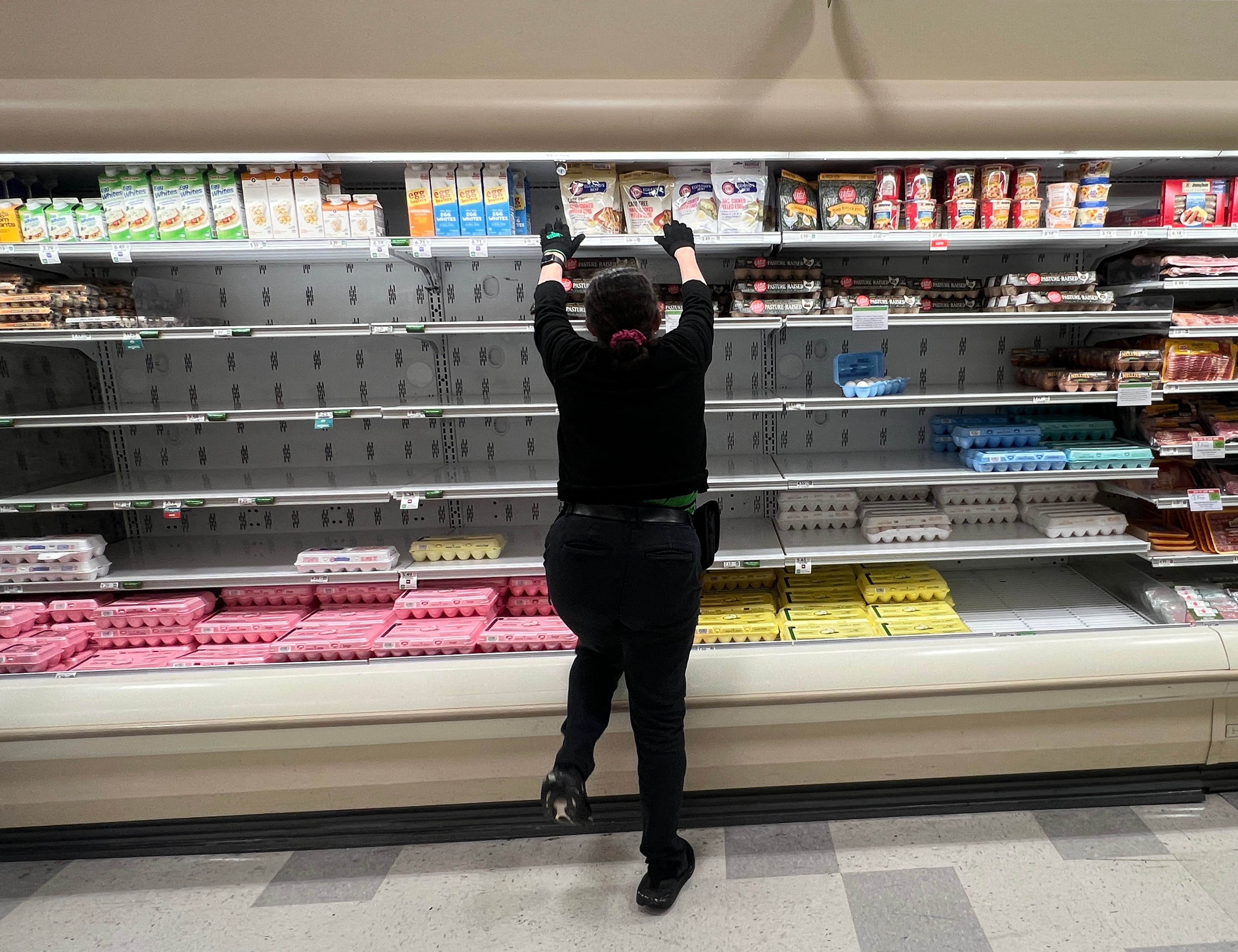 Un trabajador de una tienda de comestibles reorganiza los artículos en la sección de huevos agotados el 23 de enero de 2025 en Miami, Florida.