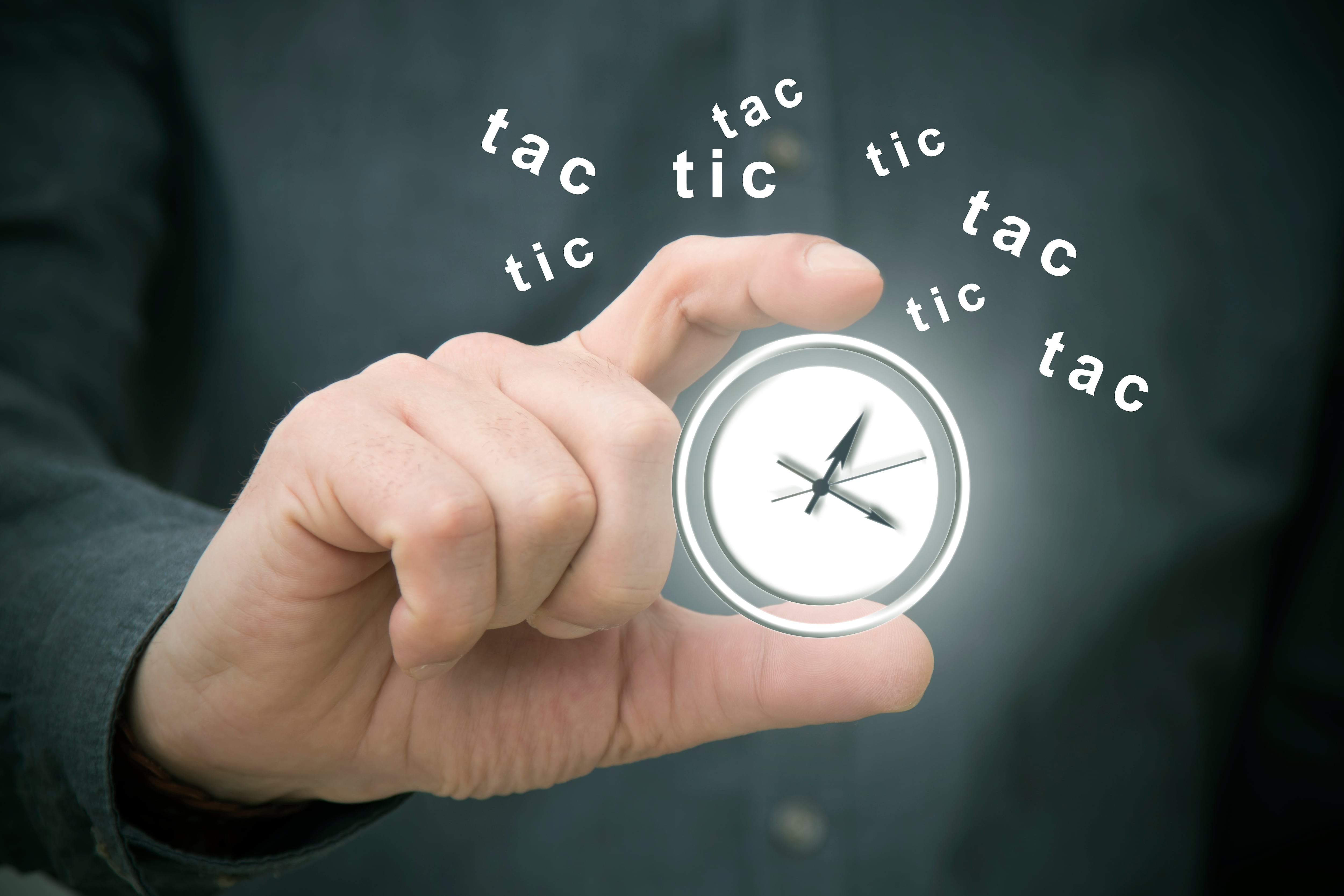 Mano sostiene reloj que marca la hora; al fondo, las palabras tic tac