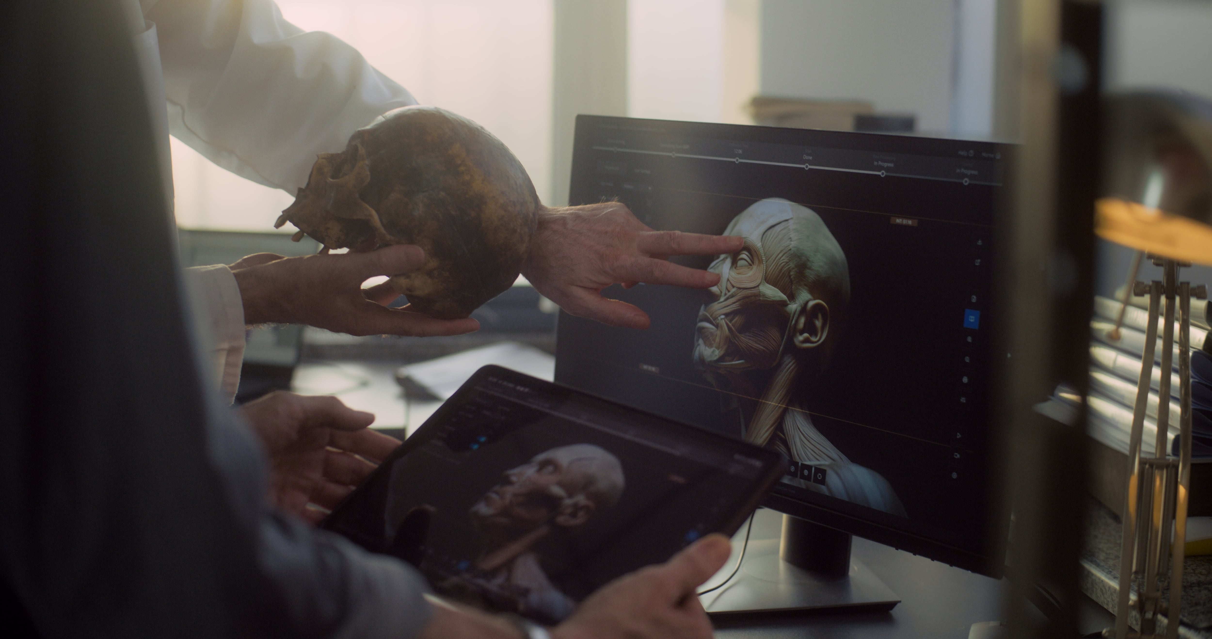 Antropología, arqueología. Laboratorio arqueológico moderno: Dos científicos analizan el cráneo fósil, discuten el modelo tridimensional y la visualización de la cabeza humana extinta prehistórica que se muestra en la tableta digital y la pantalla de la computadora.
