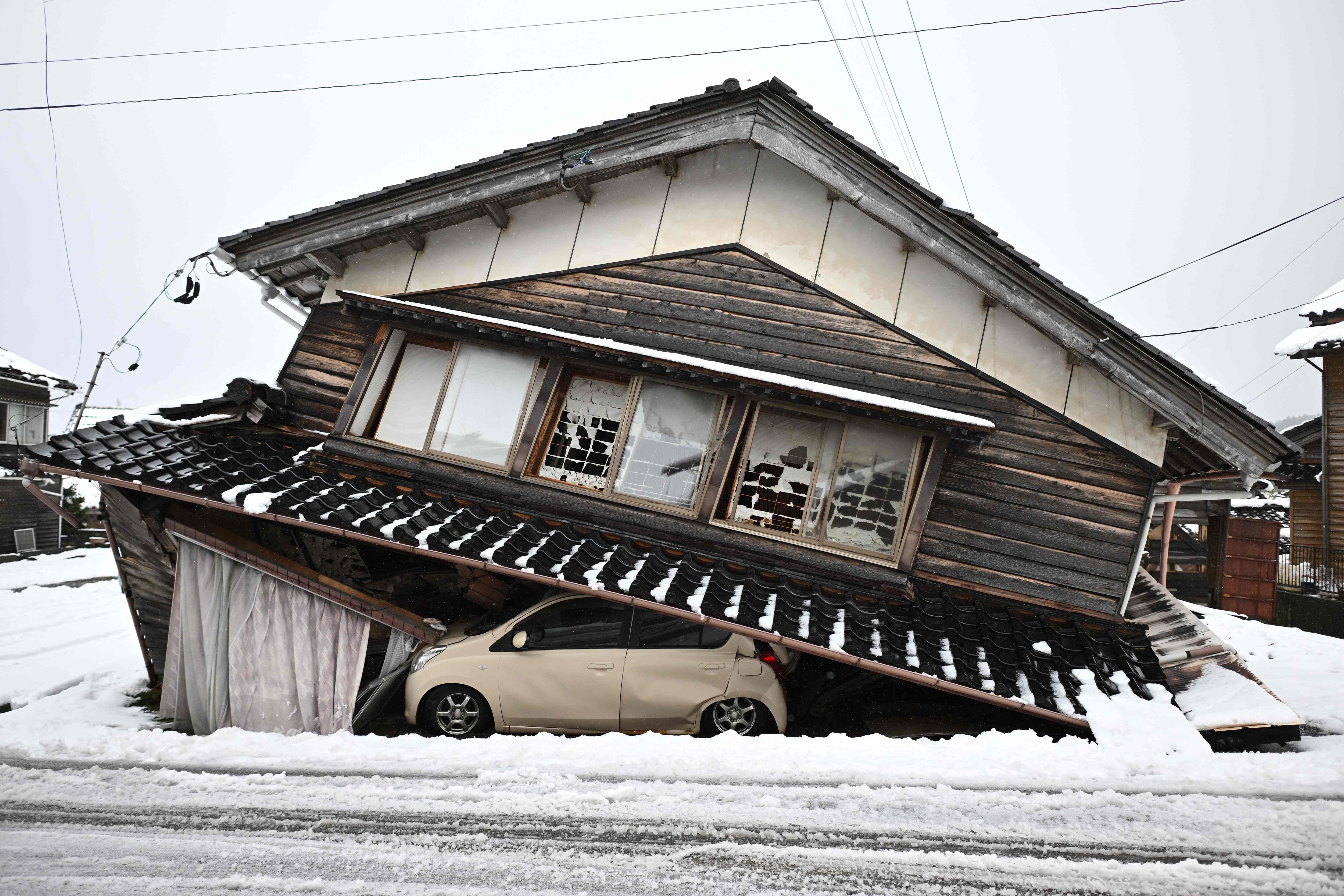 Un automóvil dañado yace debajo de un edificio derrumbado en la ciudad de Shika en el distrito de Hakui, prefectura de Ishikawa después de que un gran terremoto de magnitud 7,5 sacudiera la región de Noto el día de Año Nuevo. (Foto de Philip FONG / AFP)
