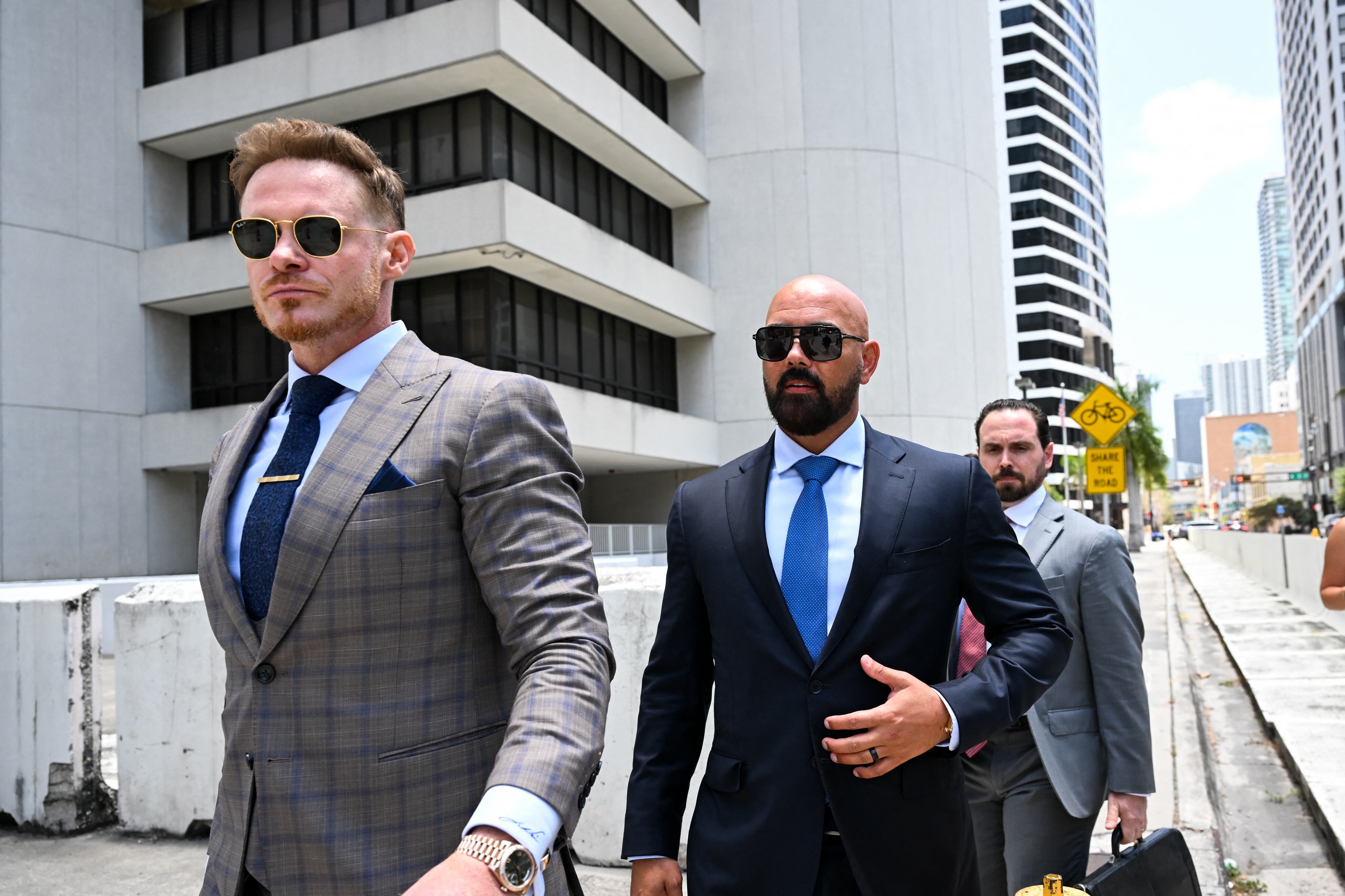 Joseph D. McBride (C), attorney for Andrew Tate and Tristan Tate, and Justin Waller (L) depart following a hearing for the Tate brothers at the C. Clyde Atkins US Courthouse in Miami, Florida, on July 20, 2026. Radical social media influencer Andrew Tate and his brother Tristan were in custody in the US on July 19, officials said, as Britain seeks their extradition to face new charges of rape, sex trafficking and assault. (Photo by CHANDAN KHANNA / AFP)