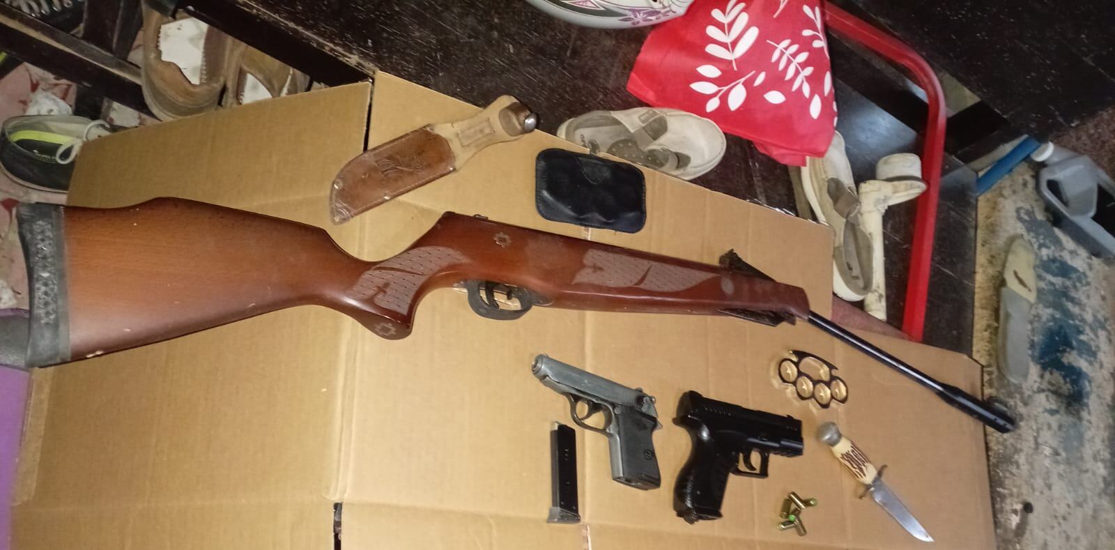 Un rifle, armas no letales, armas blancas y un celular con parte de lo decomisado en la casa donde un hombre ttenía en una especie de encierro a su familia. Foto: Cortesía MSP.