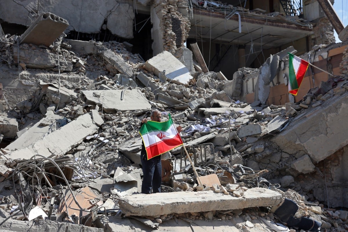 Un hombre sostiene una bandera iraní en medio de los escombros de un edificio destruido tras los bombardeos en el centro de Teherán el 4 de marzo de 2026.
