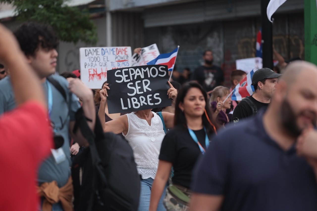 Cientos de personas con carteles y banderas se dirigen al Plantón por la Justicia Democrática en la plaza de la Democracia en San José.