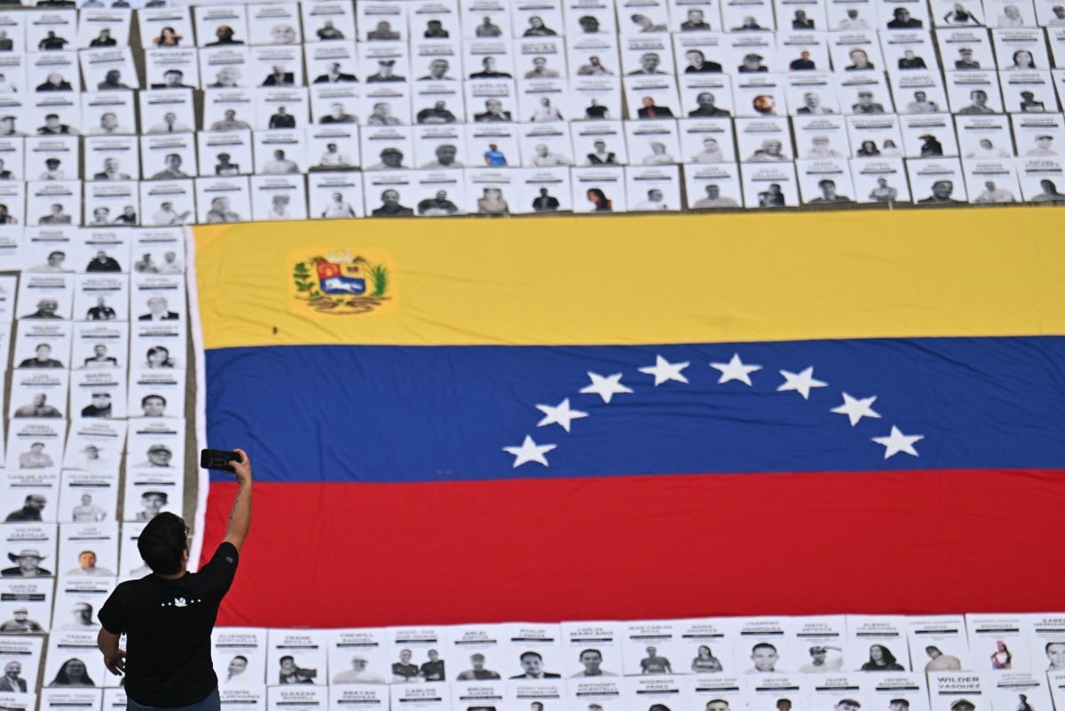 Un hombre toma una fotografía de retratos de presos políticos durante una manifestación de familiares en la Universidad Central de Venezuela, en Caracas, el 13 de enero de 2026.