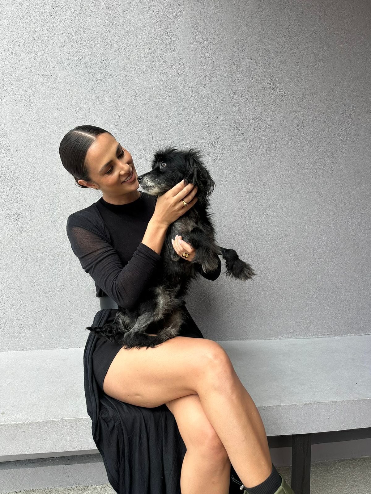 Imagen de Karina Ramos usando un vestido de color negro y con su perro Tommy en sus brazos.
