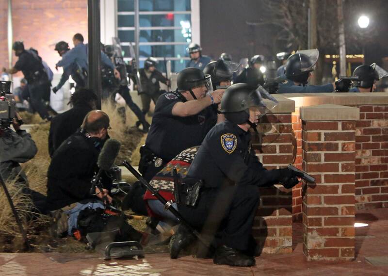 Agentes de la Policía se cubren después que dos de sus compañeros fueron heridos ayer mientras permanecían de guardia enfrente de la estación en Ferguson, Misuri. | AP