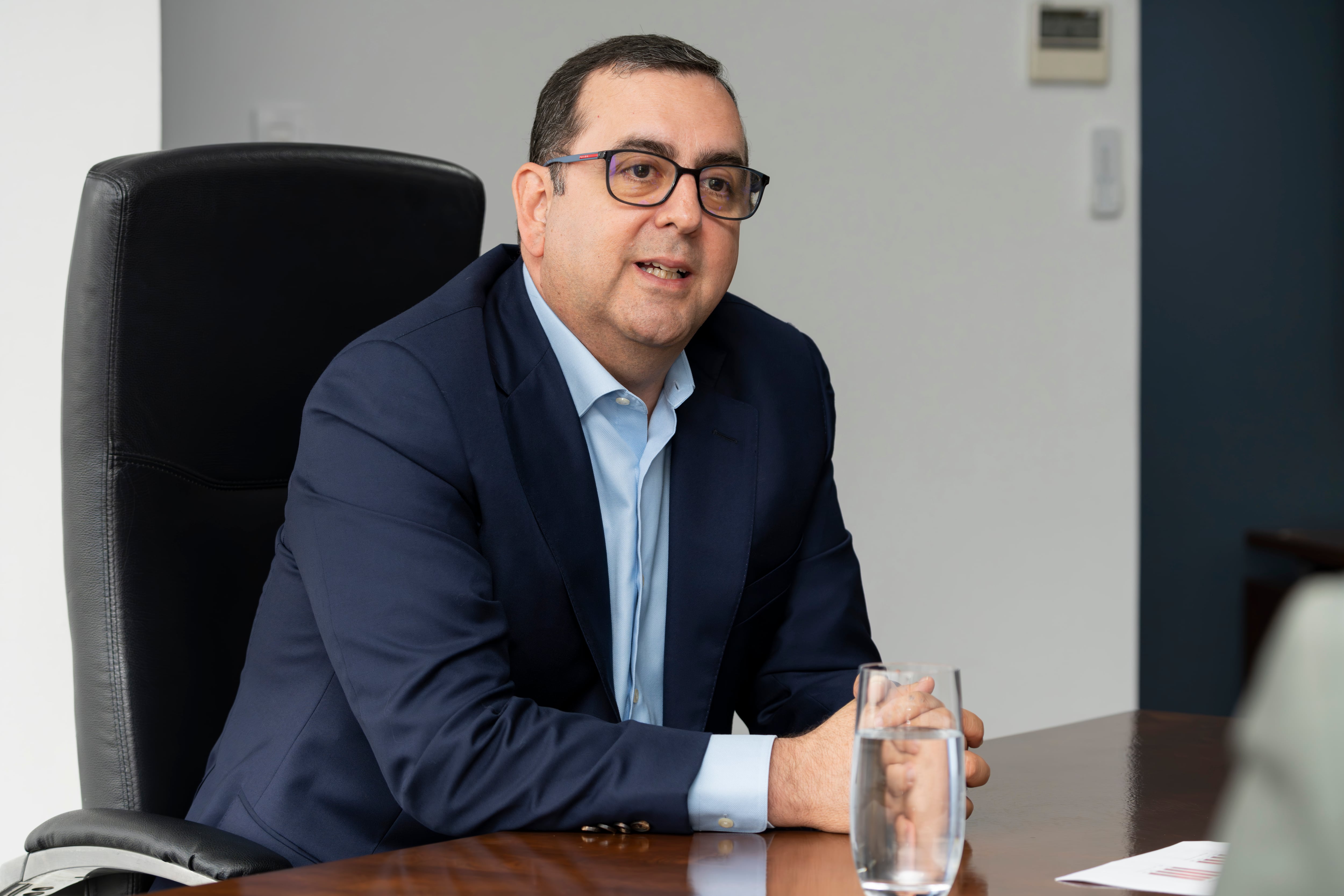 Arturo Giacomin, presidente ejecutivo de Davivienda Costa Rica, sentado en una oficina con traje azul, conversando durante una entrevista sobre la fusión entre Davivienda y Scotiabank.