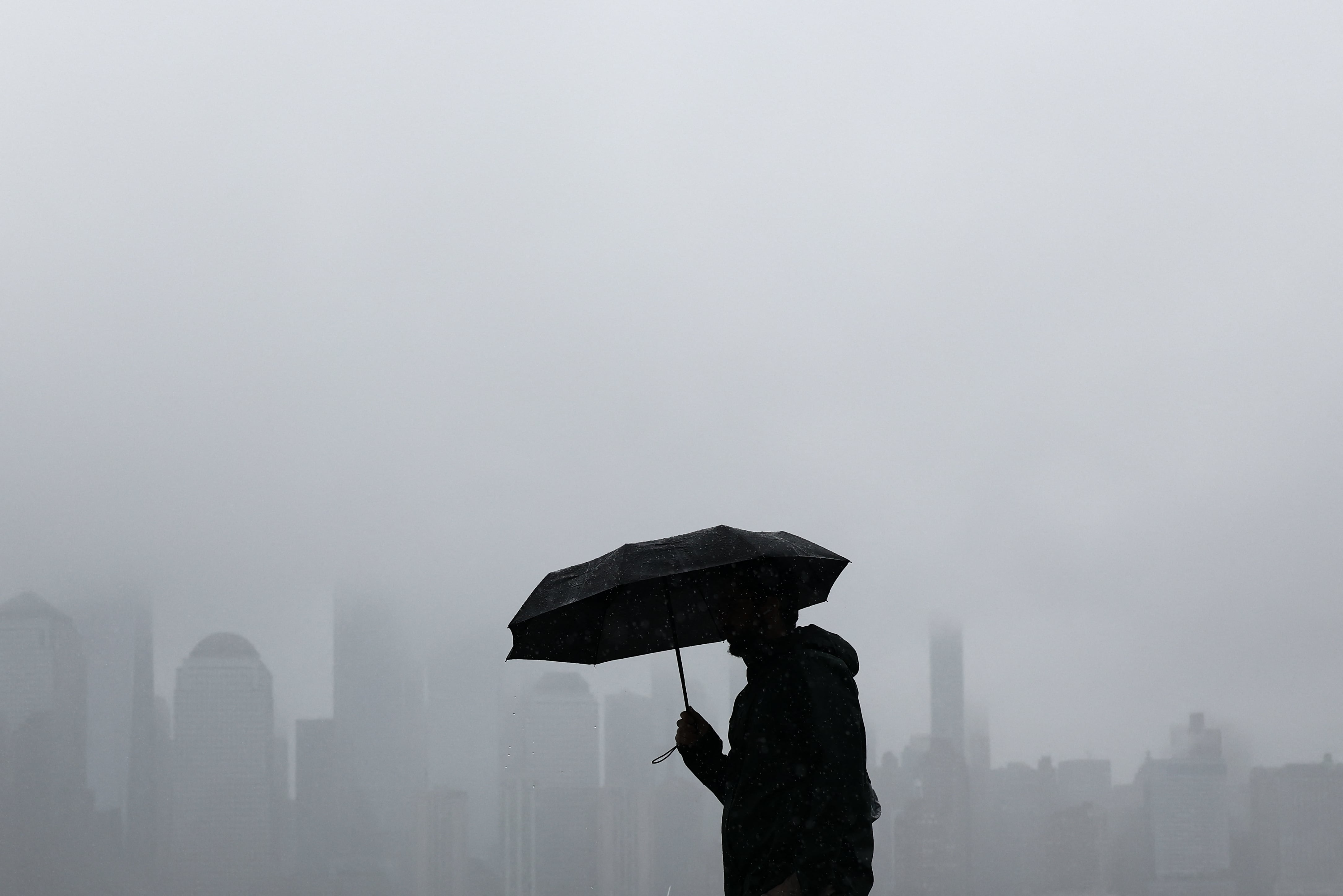 Una persona camina por la ribera de Jersey City, Nueva Jersey, mientras el perfil de Lower Manhattan se vislumbra entre la niebla, el 27 de setiembre de 2026.
