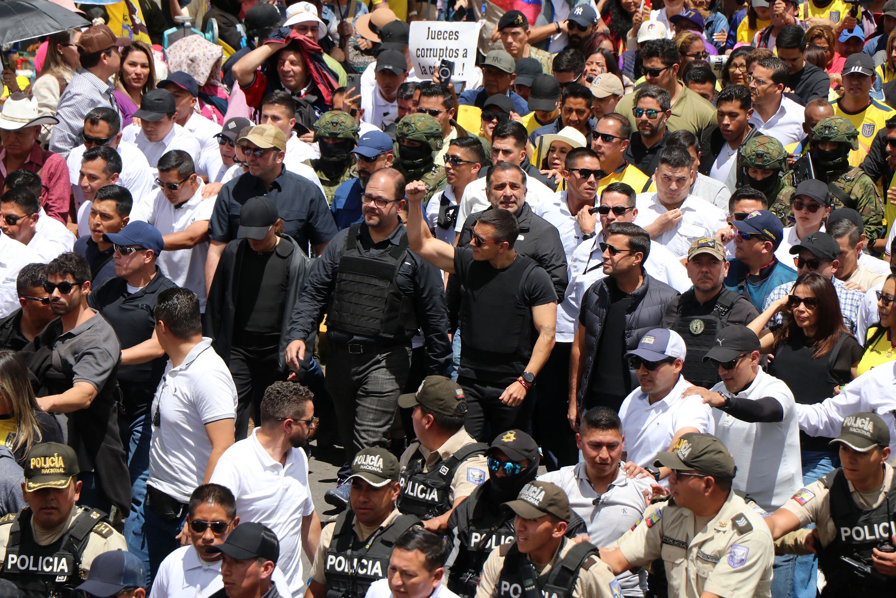 Ecuador's President Daniel Noboa (C, right) and Interior Minister John Reimberg (C, left) walk wearing bulletproof vests during a march against the Constitutional Court's decision to censor several articles of recent laws in Quito on August 12, 2025. (Photo by Galo Paguay / AFP)