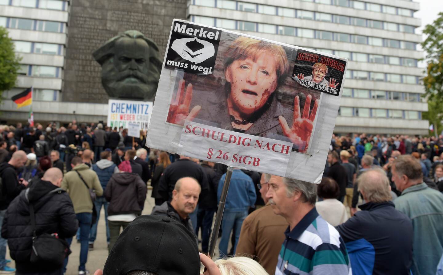 A protestor holds a poster with a photo of Angela Merkel referring reading she is guilty of incitement in Chemnitz, eastern Germany, Saturday, Sept. 1, 2018, after several nationalist groups called for marches protesting the killing of a German man last week, allegedly by migrants from Syria and Iraq. (AP Photo/Jens Meyer)