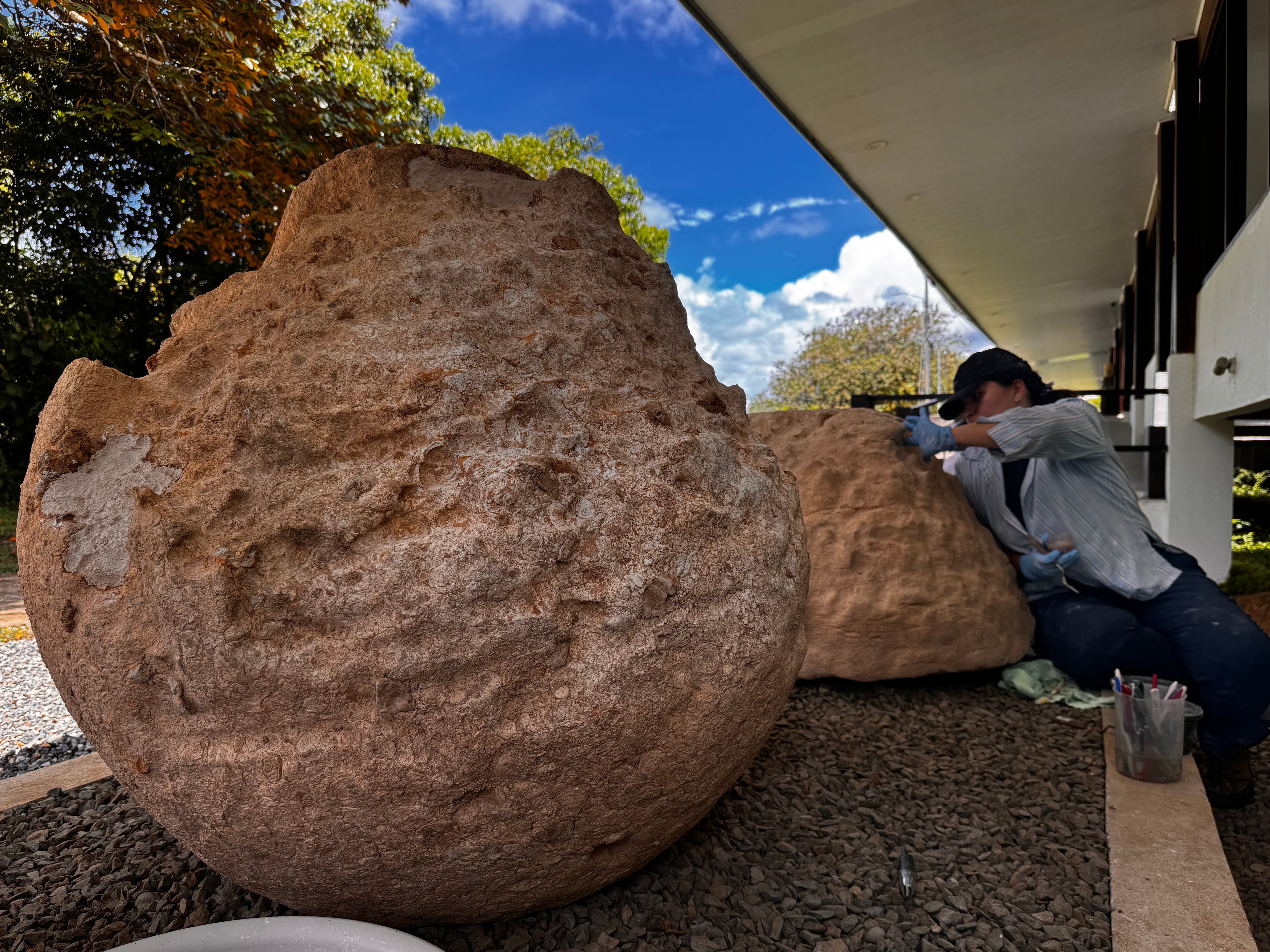 En primer plano, las esferas de piedra, detrás, una mujer restaurándolas.