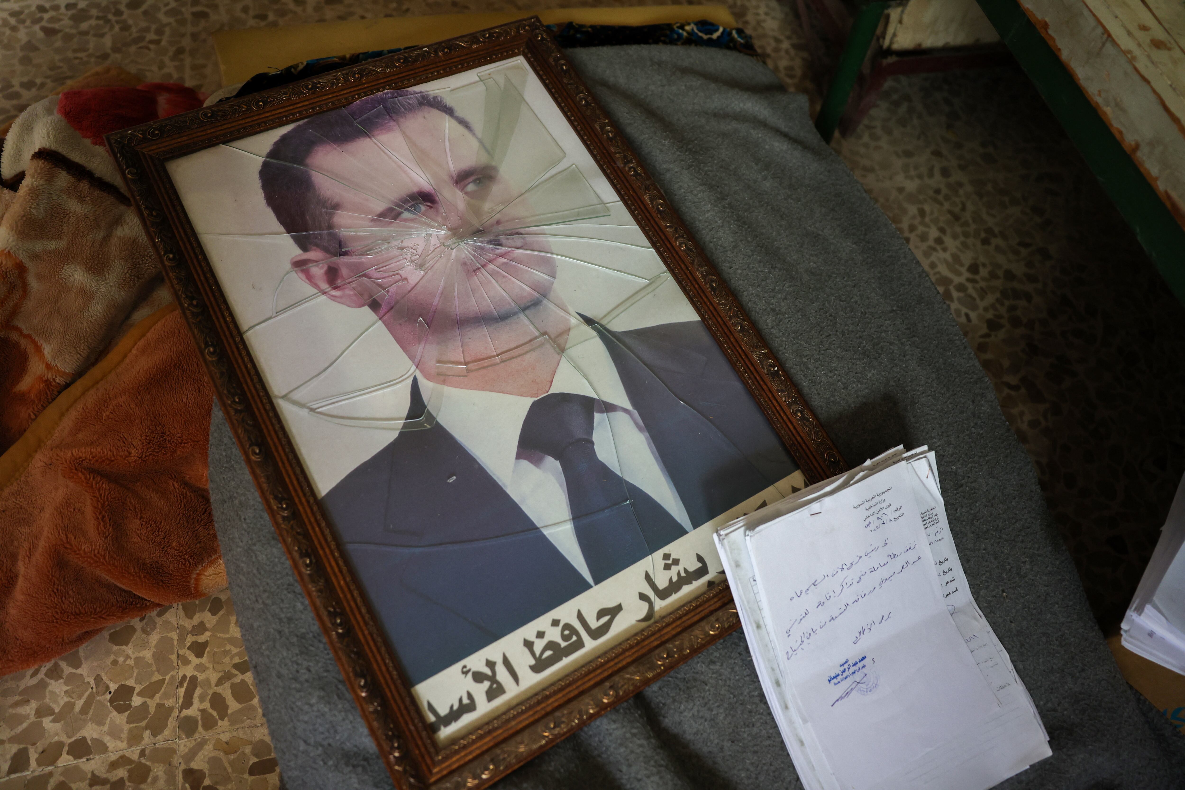 Un retrato del presidente sirio Bashar al-Assad aparece con el marco roto en una instalación de la División de Seguridad Política del régimen sirio en las afueras de la ciudad central de Hama, luego de la captura del área por fuerzas antigubernamentales, el 7 de diciembre de 2024.