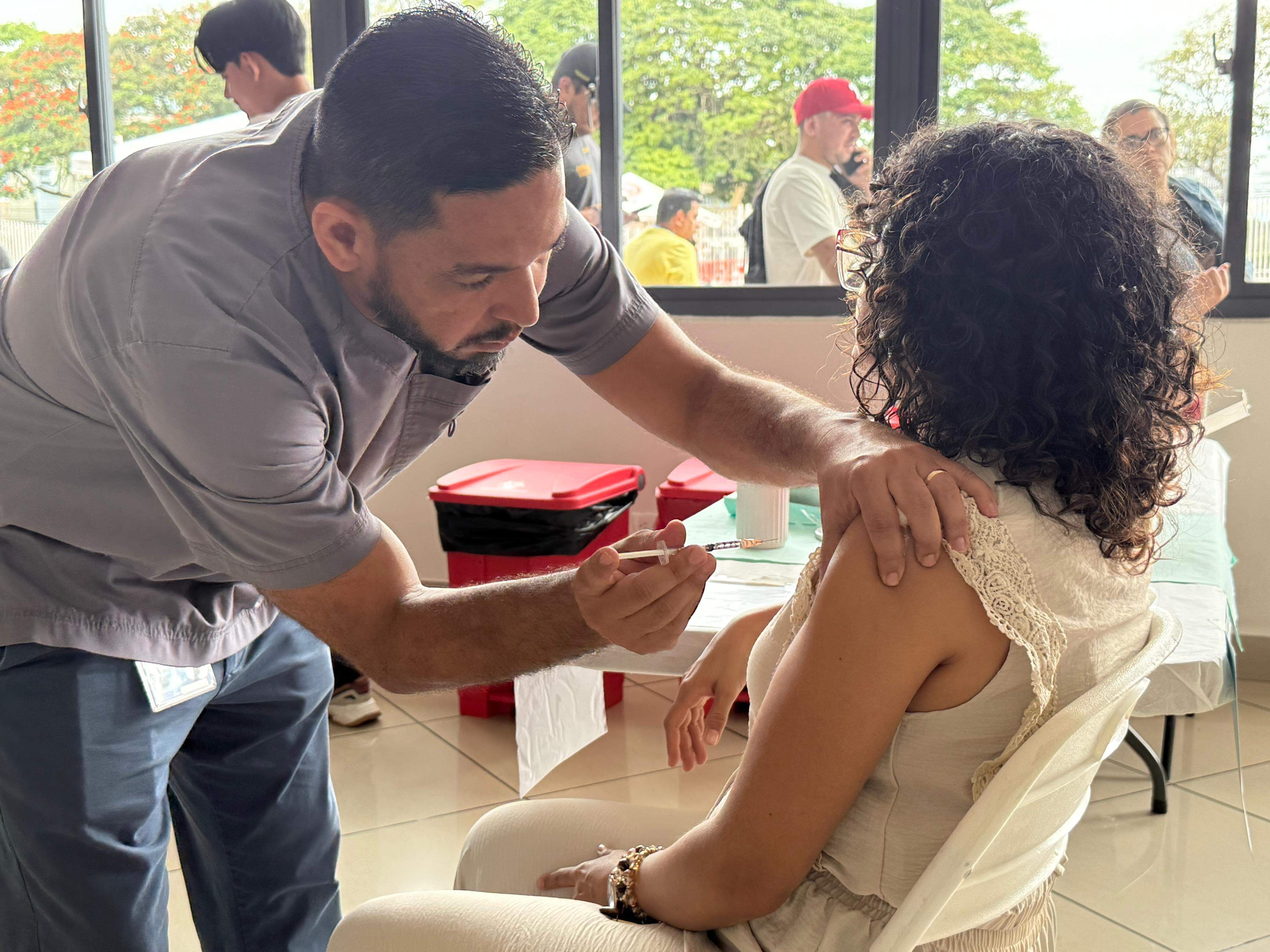 Un hombre vacuna a una mujer. La inyección se administra en el brazo.