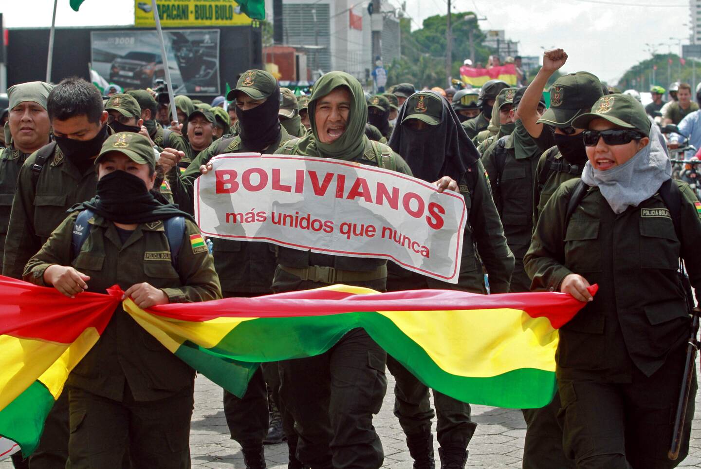 Police officers take part in a march to protest against Bolivian President Evo Morales with a sign reading "Bolivians more united than ever" in Santa Cruz, Bolivia, on November 9, 2019. - Police in three Bolivian cities joined anti-government protests Friday, in one case marching with demonstrators in La Paz, in the first sign security forces are withdrawing support from President Evo Morales after a disputed election that has triggered riots. (Photo by DANIEL WALKER / AFP)