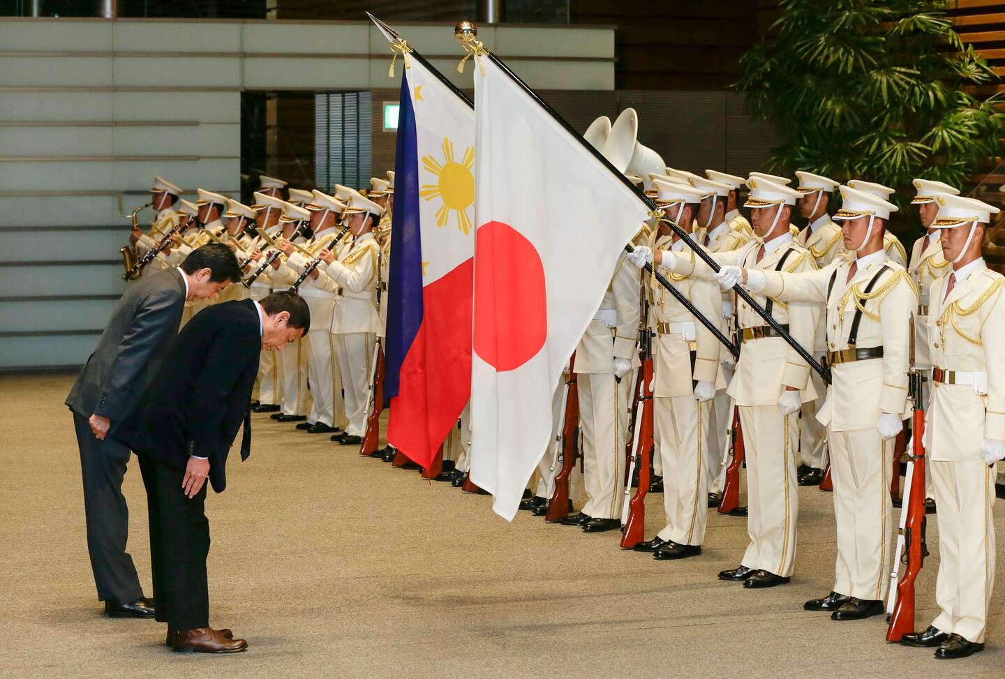 El presidente de Filipinas, Rodrigo Duterte (der.) saluda las banderas de Filipinas y Japón junto al Primer Ministro japonés Shinzo Abe (izq.) en Tokio, este miércoles 26.