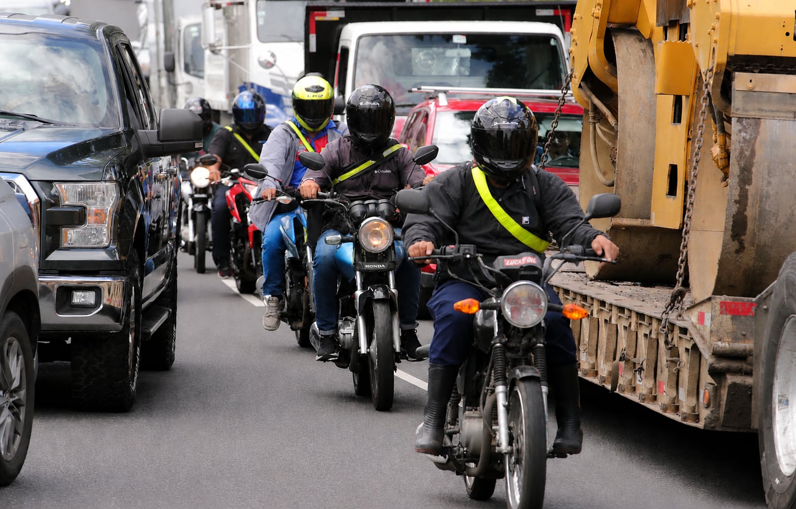 Motociclistas, motos, motocicletas en medio del tráfico abriéndose paso en carril inexistente. Presas. Congestionamiento. Congestión vial