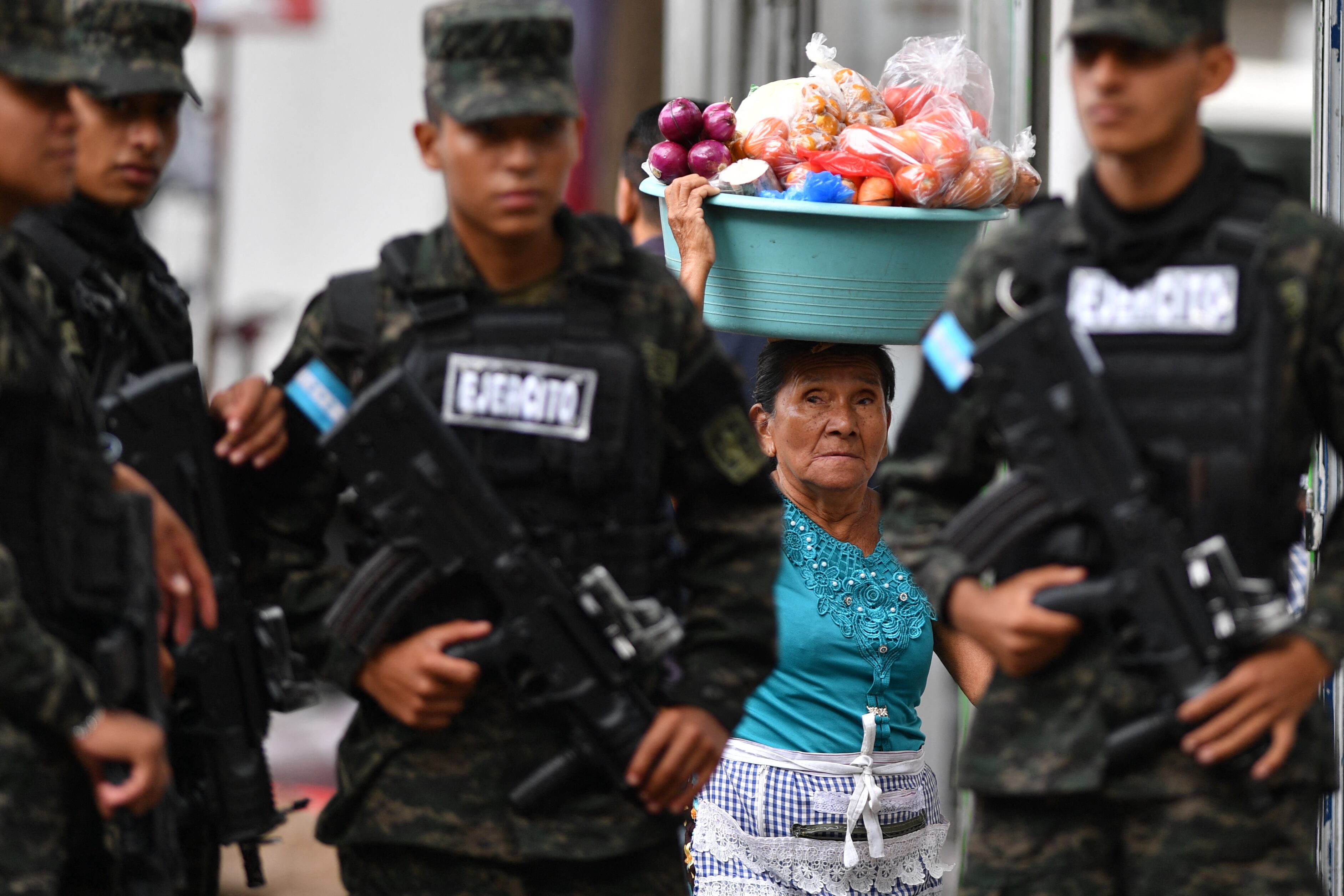 Una vendedora de verduras observa mientras soldados montan guardia en el Parque Central de Tegucigalpa, el 1 de noviembre. Candidatos presidenciales en Honduras se acusan de preparar fraude electoral a semanas de los comicios del 30 de noviembre, en un ambiente de tensión política y denuncias de injerencia militar. Fotografía: