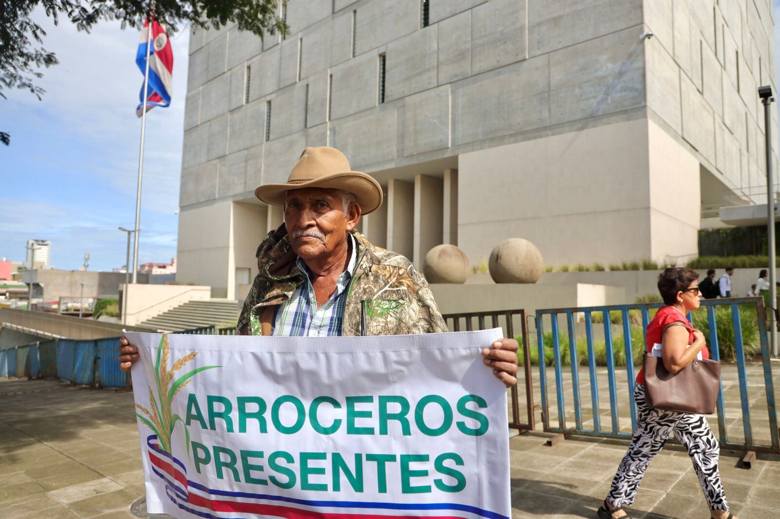 Un productor de arroz sostiene un rótulo que dice "Arroceros presentes".