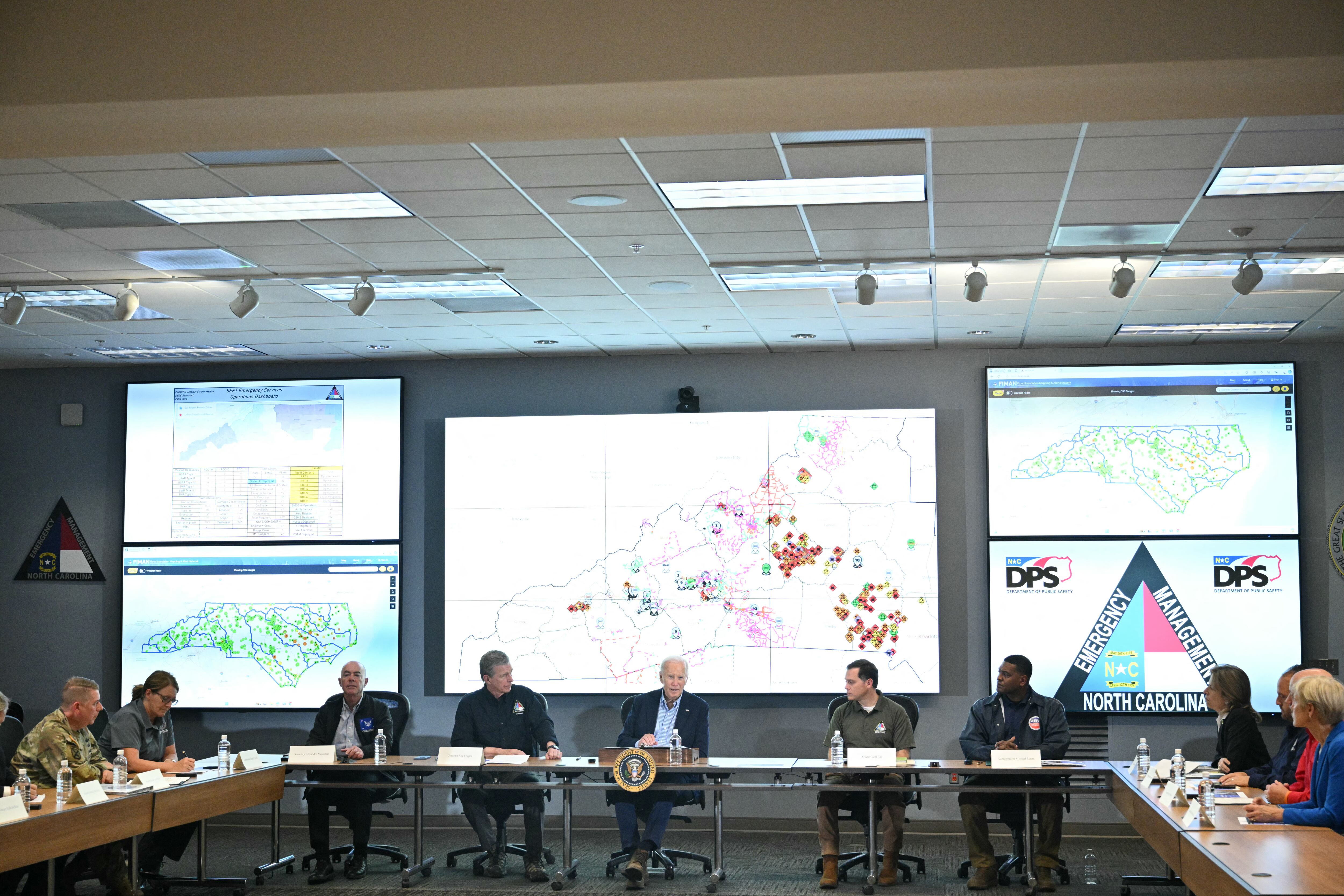 El secretario de Seguridad Nacional de Estados Unidos, Alejandro Mayorkas (izq.), y el gobernador de Carolina del Norte, Roy Cooper (segunda izq.), escuchan al presidente de Estados Unidos, Joe Biden, hablar durante una sesión informativa operativa en el Centro de Operaciones de Emergencia de Raleigh tras el paso del huracán Helene, en Raleigh, Carolina del Norte.