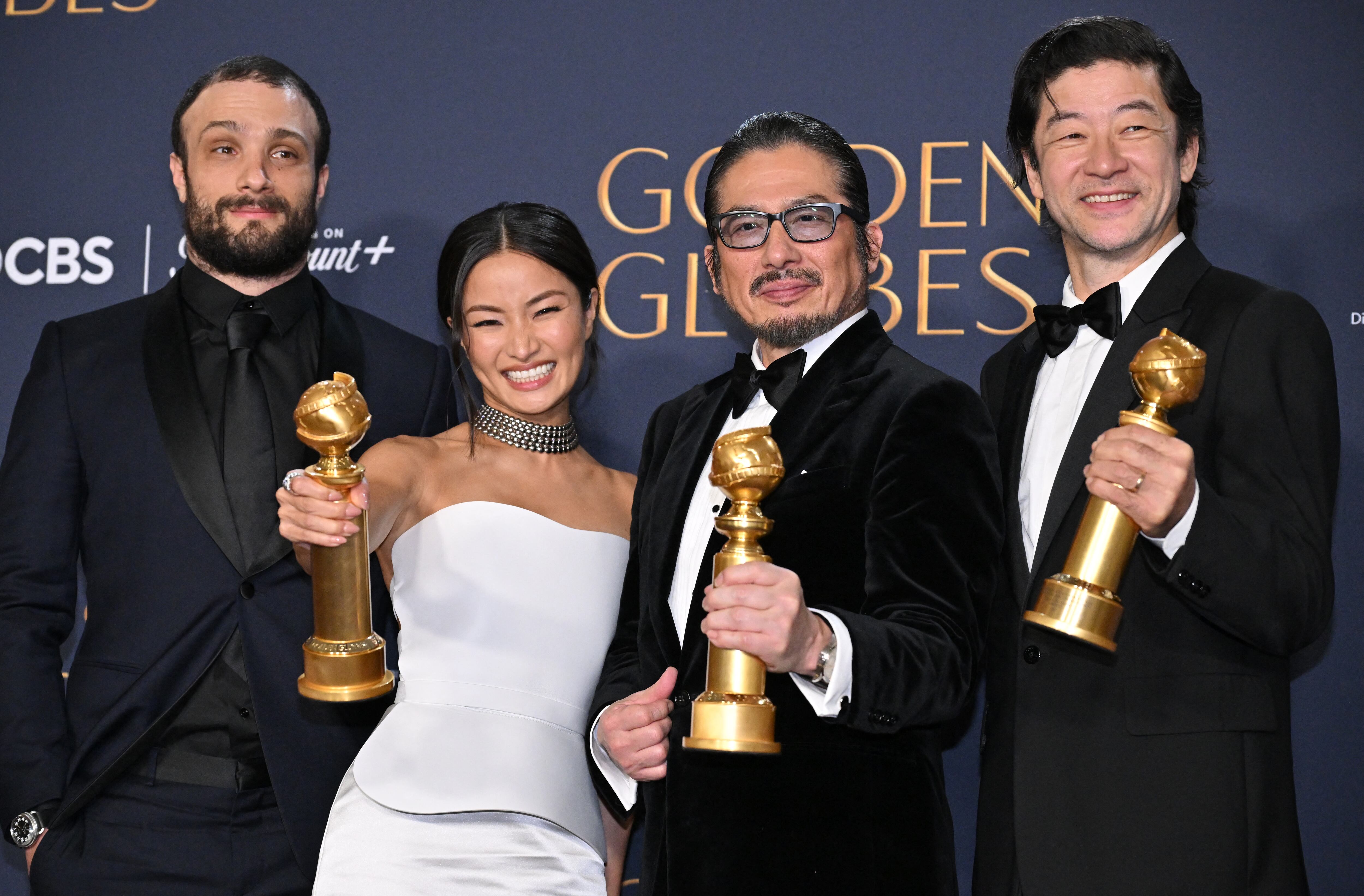 Imagen en la que se ven el británico Cosmo Jarvis, la actriz japonesa Anna Sawai, el director Hiroyuki Sanada y el actor Tadanobu Asano posando para una fotografía mientras sostienen sus premios Globos de Oro. Los hombres visten con traje de color negro y la actriz usa un vestido blanco.