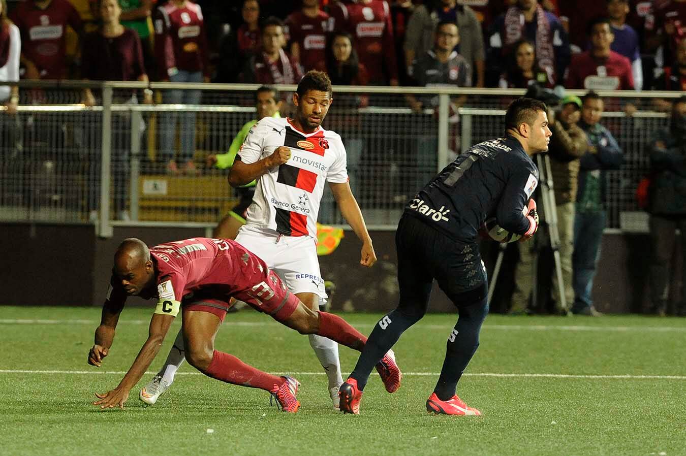 El arquero Danny Carvajal atrapa la pelota ante la mirada del mediocampista de Alajuelense Armando Alonso.