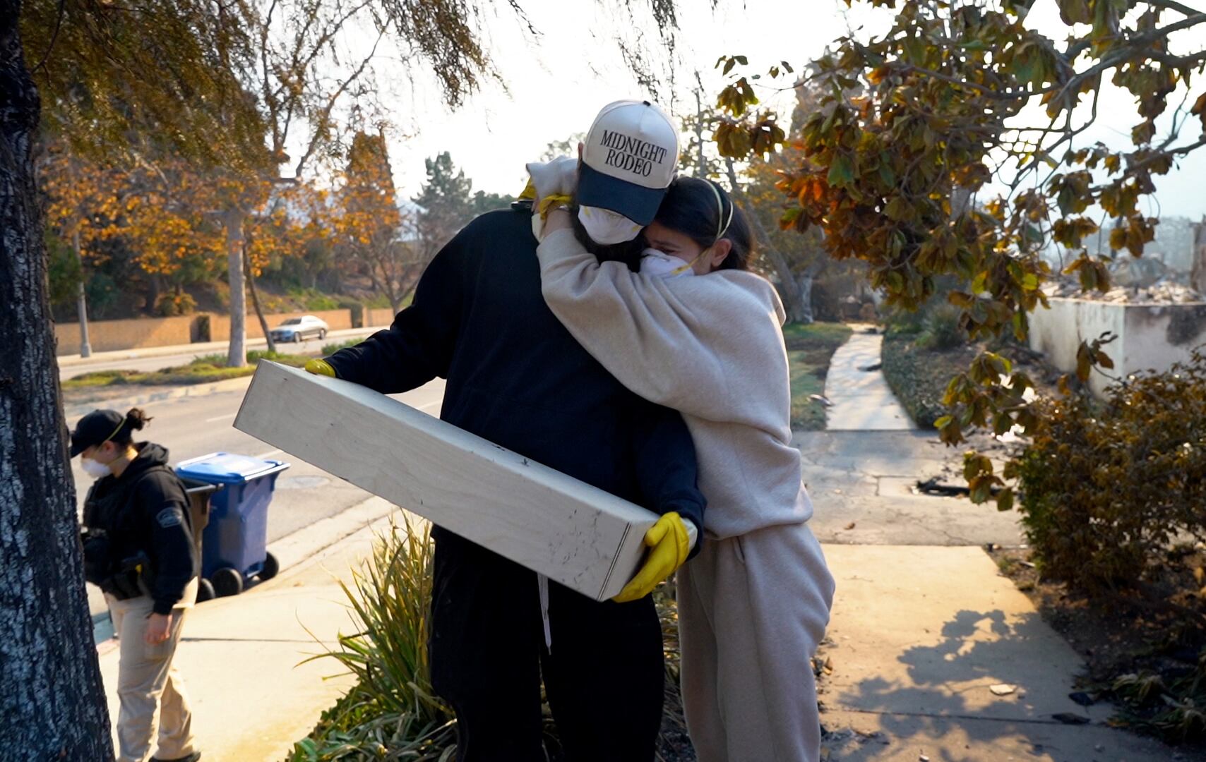 Nicole Perri y Kyle Kucharski se abrazan mientras solo encuentran una caja de vino en las ruinas de su casa destruida por el incendio de Palisades en el vecindario de Pacific Palisades de Los Ángeles, California.