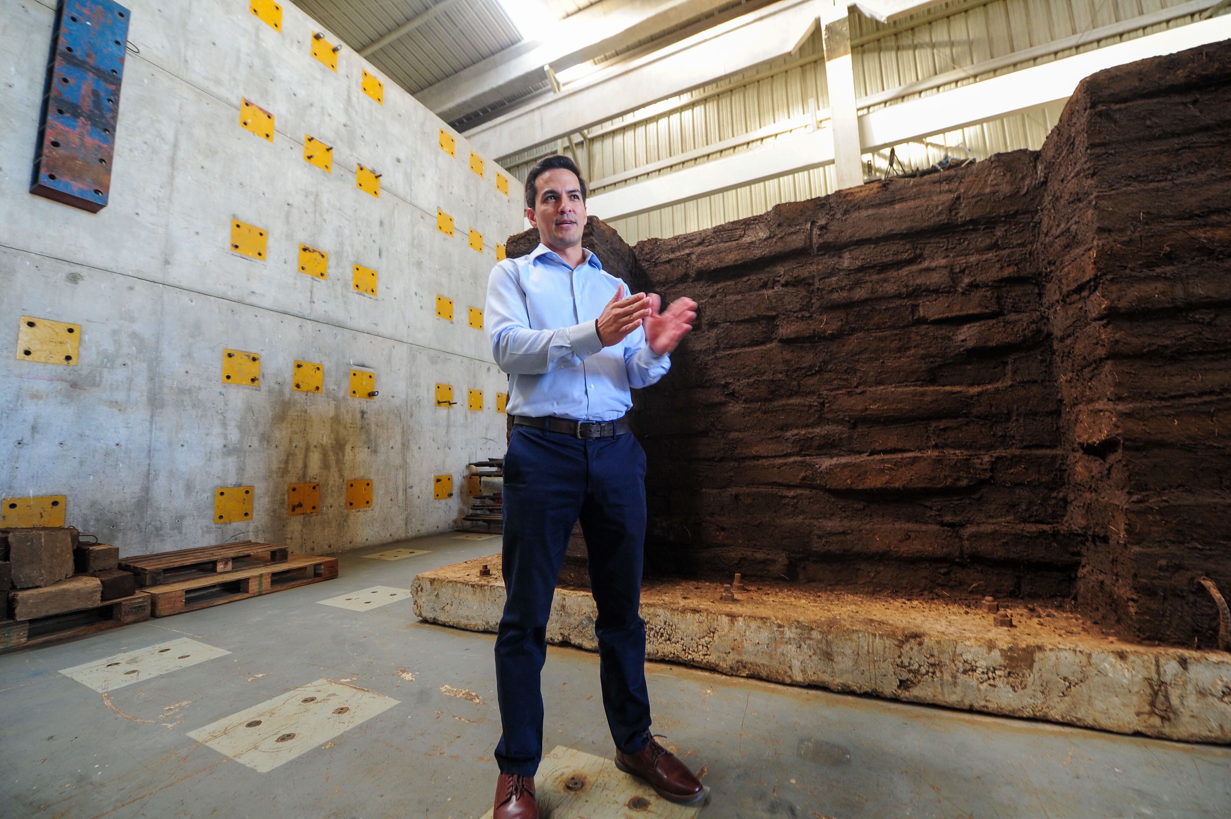 En primer plano, el investigador Diego Hidalgo Leiva, en segundo plano, el muro de adobe que busca soportar diferentes terremotos.