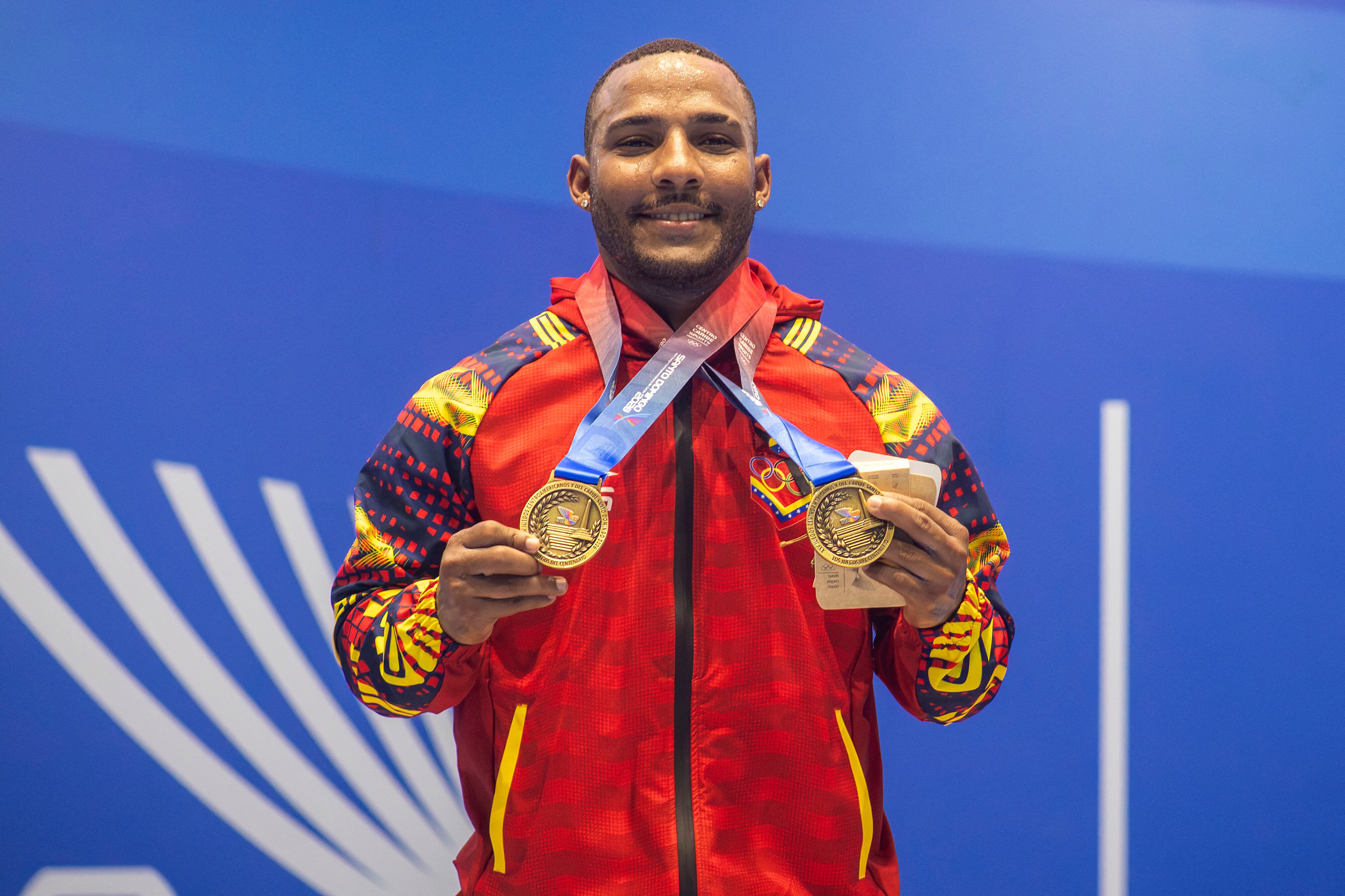 El levantador de pesas venezolano Julio Mayora muestra con orgullo su doble medalla de oro en la categoría de 79 kilos en los Juegos Centroamericanos y del Caribe Santo Domingo 2026.