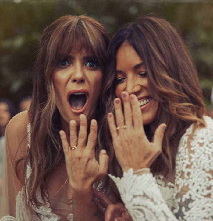 Kany García y su esposa mostrando sus anillos de compromiso y vestidas de novia el día de su boda.