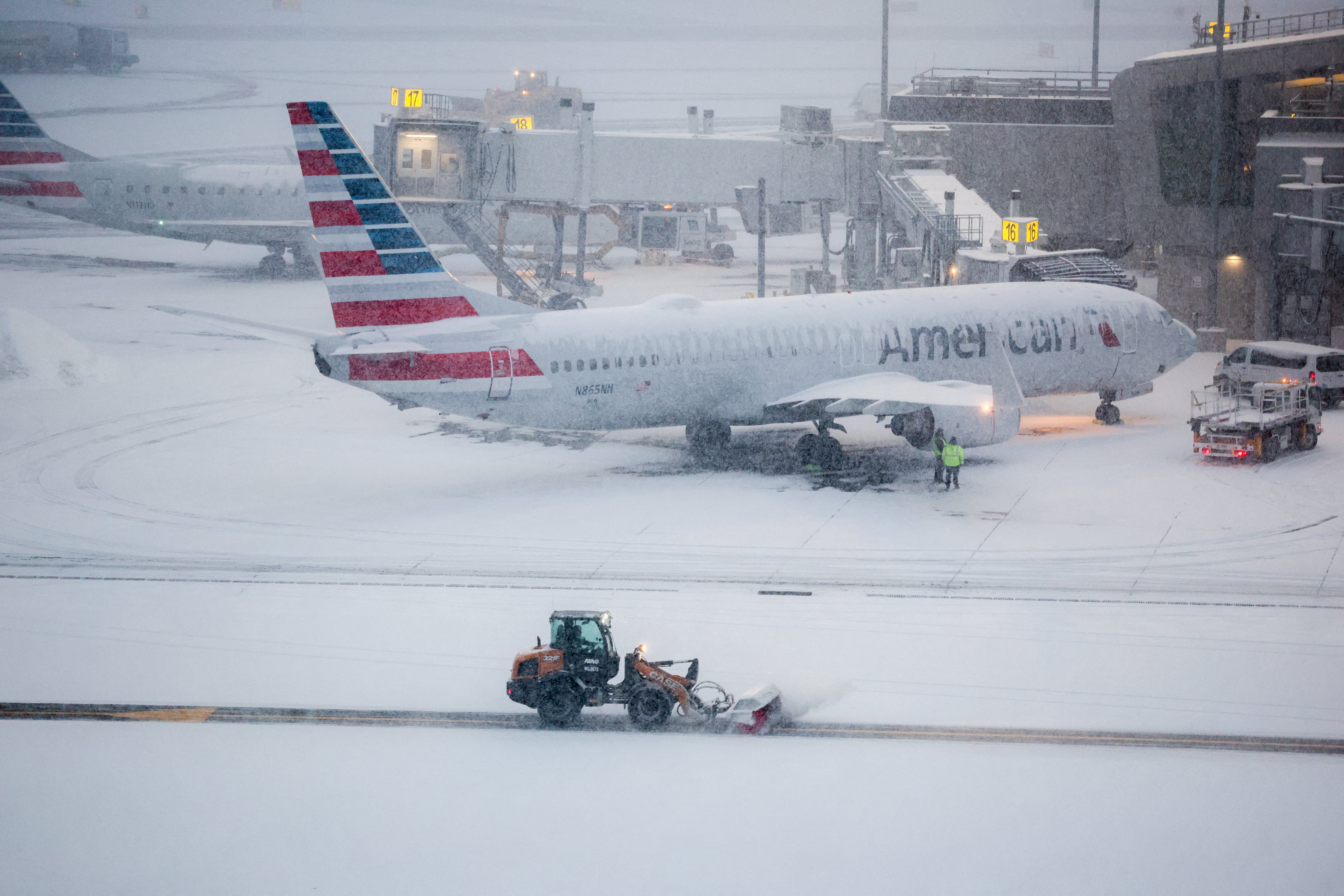 Una máquina quitanieves en funcionamiento mientras un avión de pasajeros Boeing 737 de American Airlines se quedó estacionado en la puerta de embarque del aeropuerto La Guardia de Nueva York este domingo 25 de enero. Fotografía: