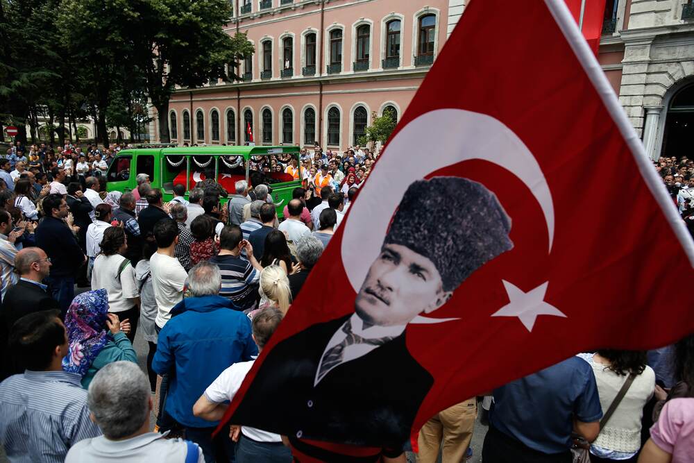 El retrato del fundador de Turquía, Mustafá Kemal Atatürk, junto a una bandera del país durante el funeral de una víctima de un atentado terrorista en la ciudad de Estambul. | AP