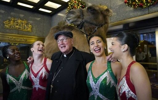 Arzobispo de Nueva York, el cardenal Timothy Dolan, y las Rockettes posan en el Radio City Music Hall de Nueva York, el 28 de octubre de 2024.