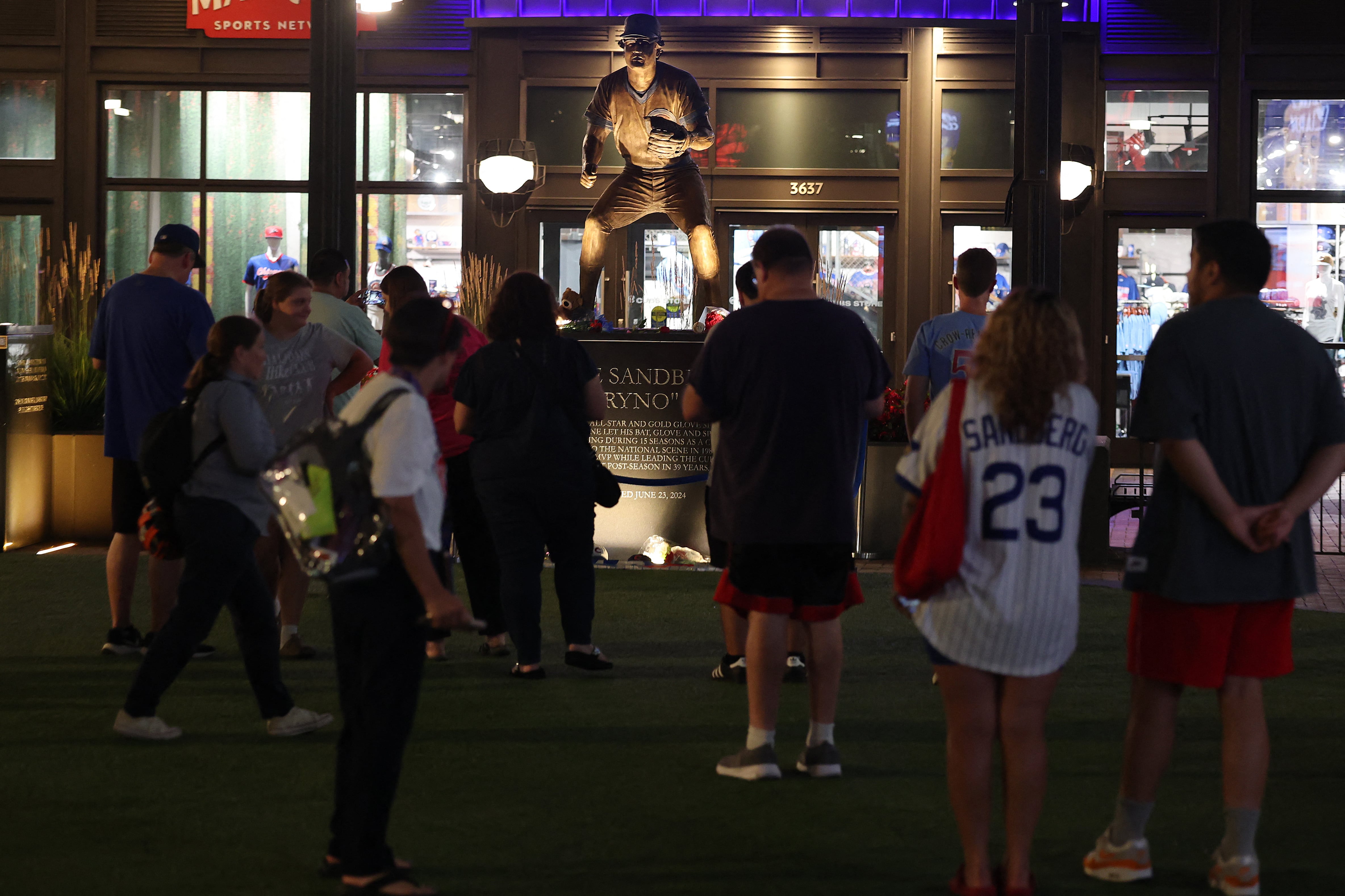 Aficionados se reúnen para rendir tributo frente a la estatua de Ryne Sandberg en el estadio Wrigley Field de Chicago, sede de los Cachorros.