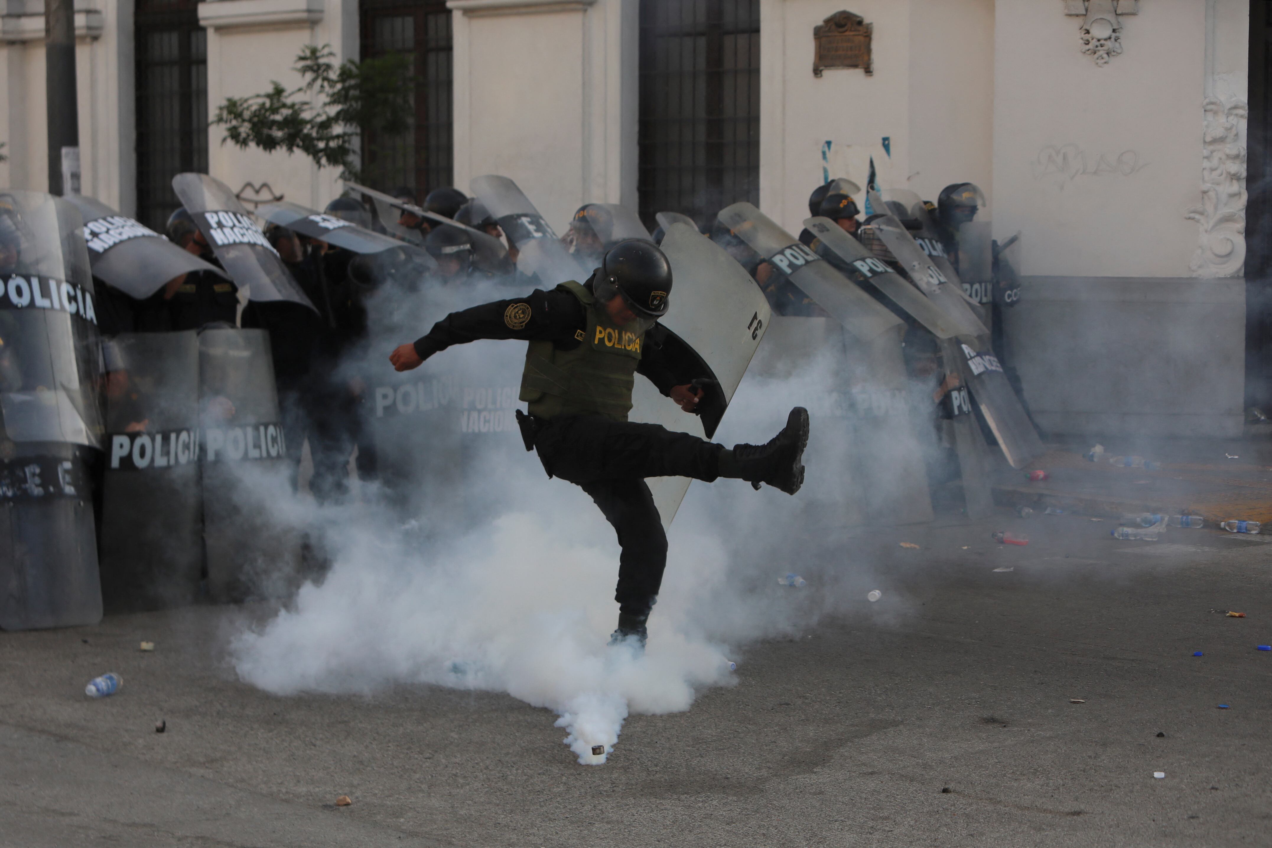 Un policía patea una bomba lacrimógena durante una manifestación contra el gobierno de la presidenta peruana Dina Boluarte en Lima el 26 de enero de 2023. - Familiares de las víctimas de las protestas en Perú exigieron este jueves "justicia" al gobierno de la presidenta Dina Boluarte, a quien culpan de las 46 muertes en 50 días de protestas a las que ahora se suma la escasez de combustible. (Foto por Lucas AGUAYO / AFP)