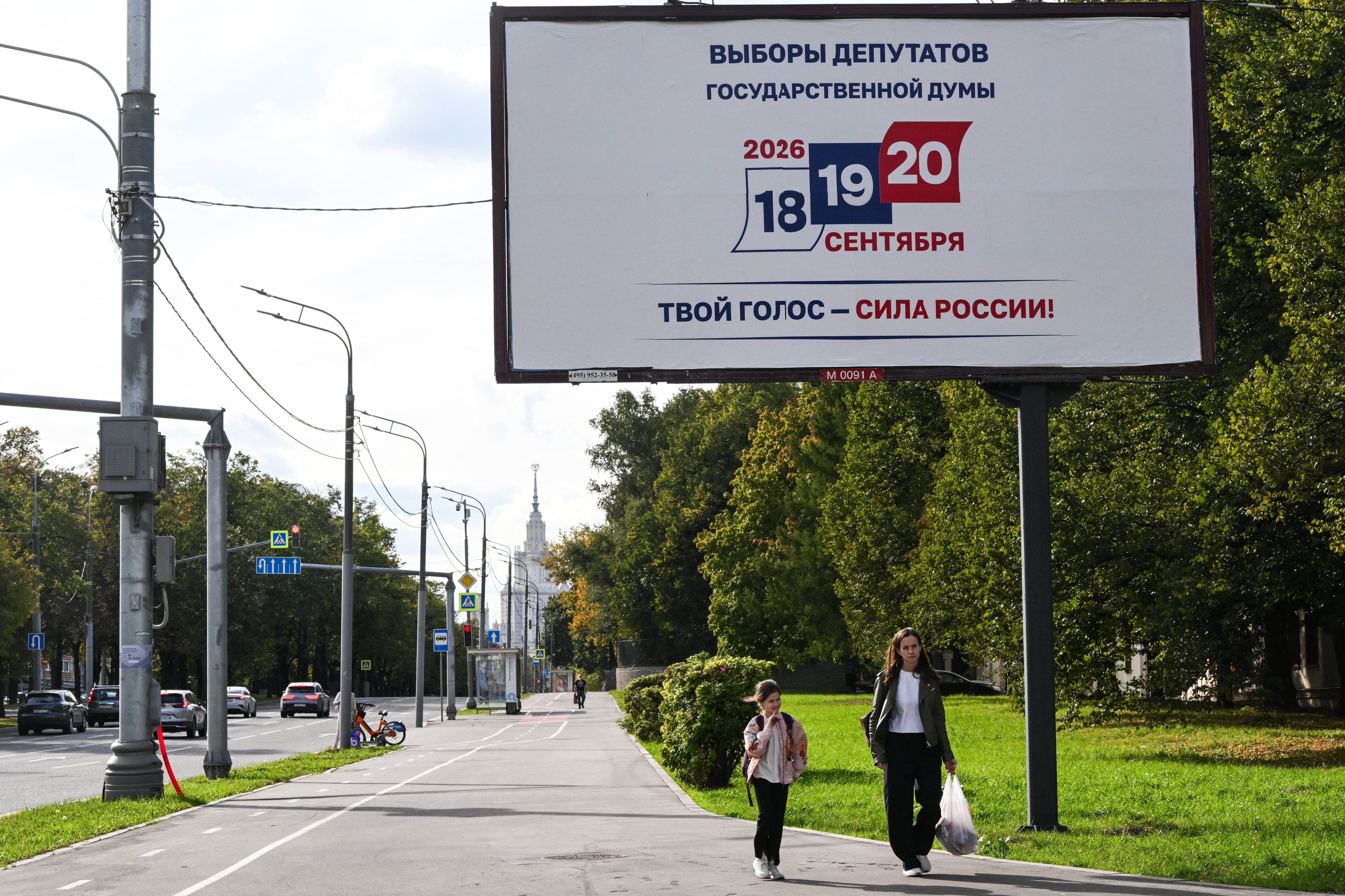 Personas caminan frente a un anuncio sobre las próximas elecciones de la Duma Estatal, la Cámara Baja del Parlamento ruso, con el edificio de la Universidad Estatal de Moscú al fondo, en Moscú, el 14 de setiembre de 2026.