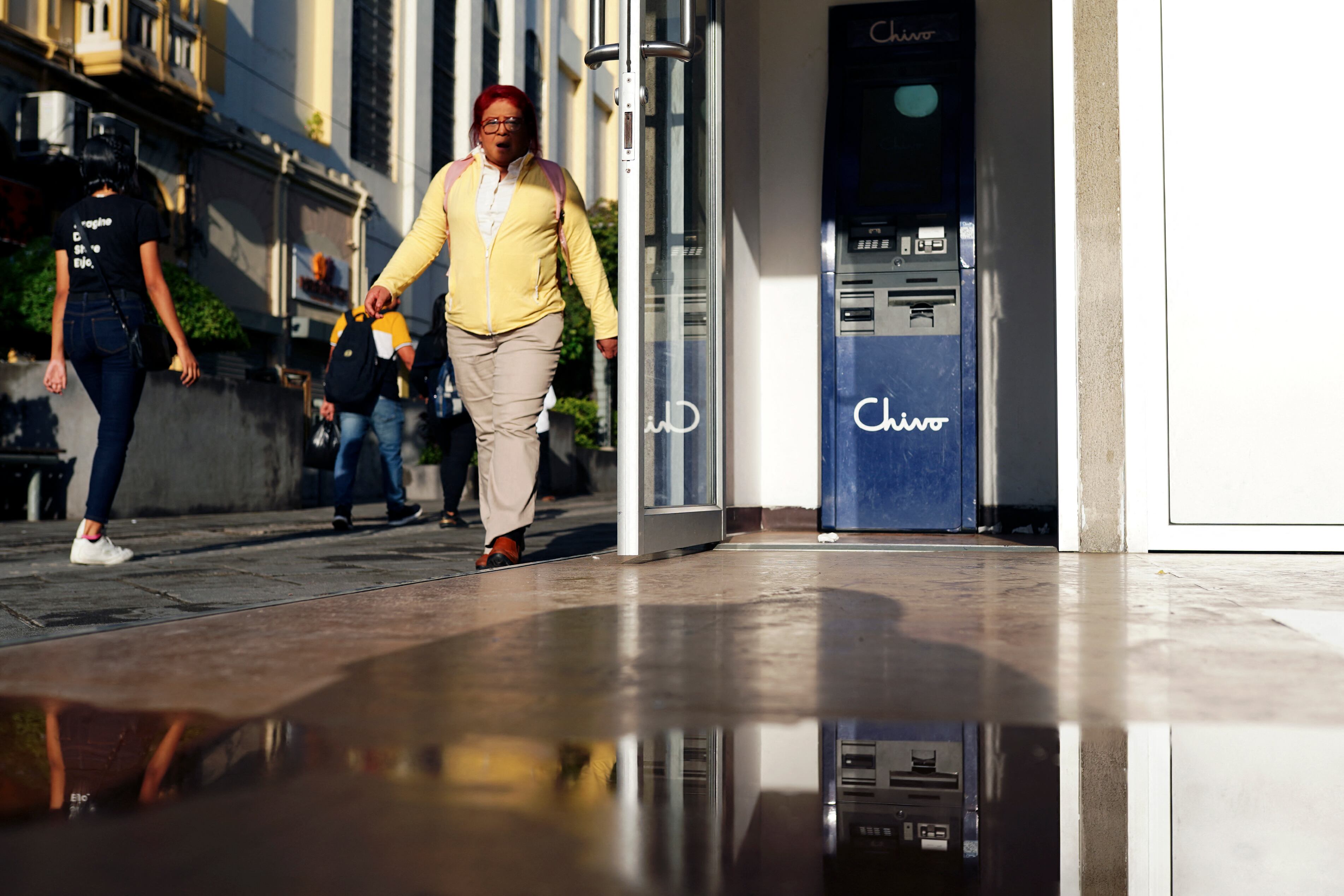 La gente camina junto a un cajero automático de la billetera electrónica estatal Chivo en el centro histórico de San Salvador