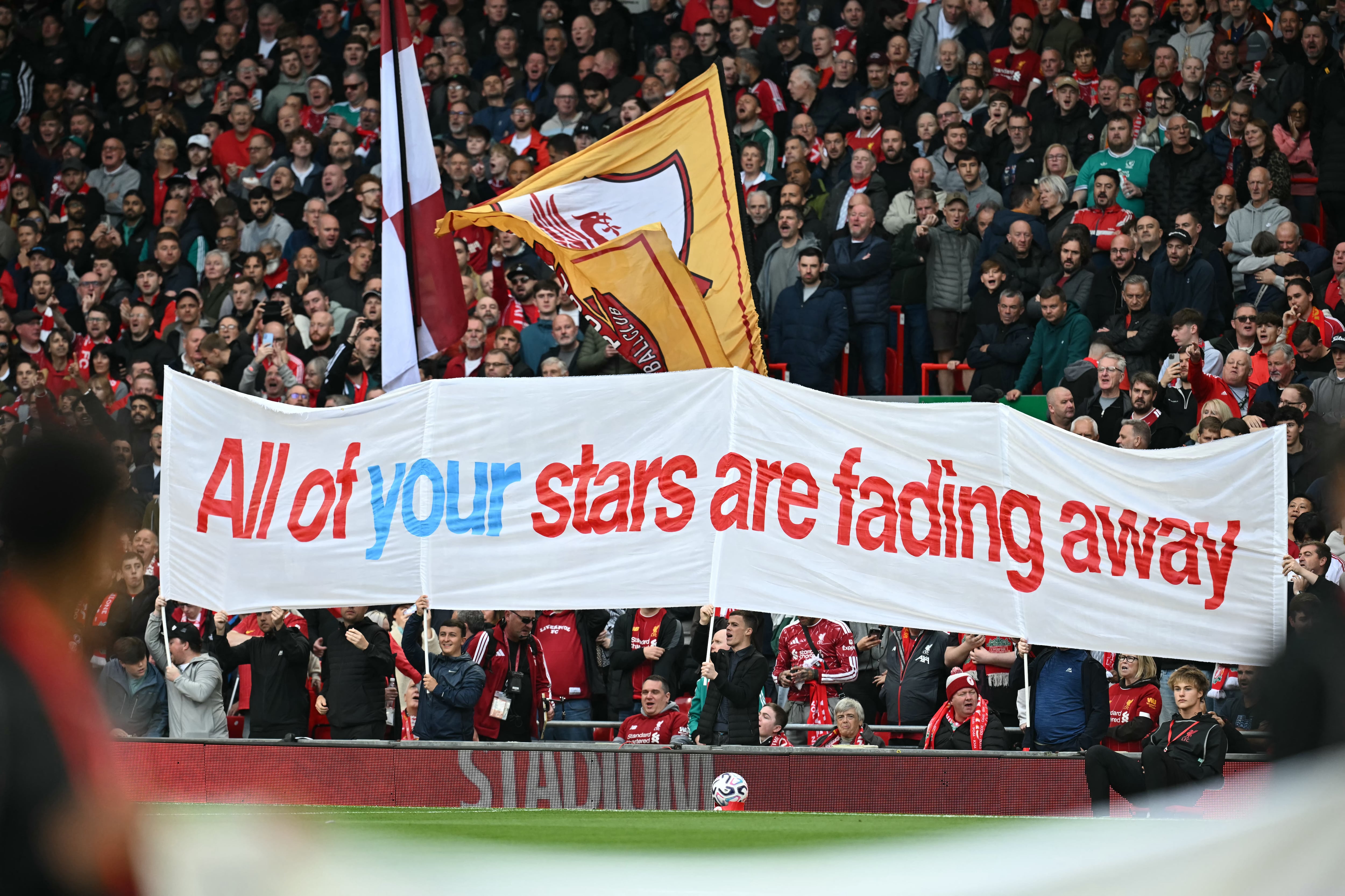 Aficionados del Liverpool mostraron este domingo 11 de octubre mantas burlándose de la situación del Manchester City; esta dice "Todas tus estrellas se están desvaneciendo".