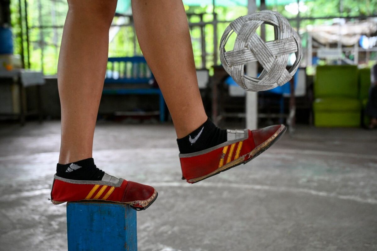This photo taken on May 25, 2025 shows female chinlone player Phyu Sin Phyo practicing for a solo Tapindaing performance during a training session in Yangon. Mastering control of the rising and falling rattan chinlone ball teaches patience, says a veteran of the traditional Myanmar sport -- a quality dearly needed in the long-suffering nation. (Photo by Sai Aung MAIN / AFP) / TO GO WITH 'MYANMAR-SPORT-CULTURE-CONFLICT-CHINLONE,FOCUS' BY LYNN MYAT AND HLA-HLA HTAY