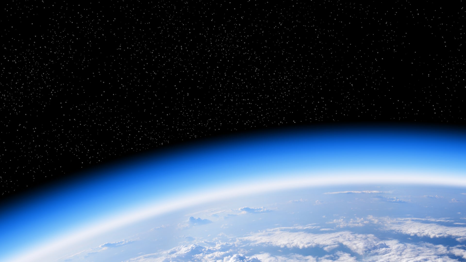 Imagen de la atmósfera terrestre vista desde el espacio, con la capa de ozono resaltada en tonos azules, fundamental para la protección contra la radiación UV.