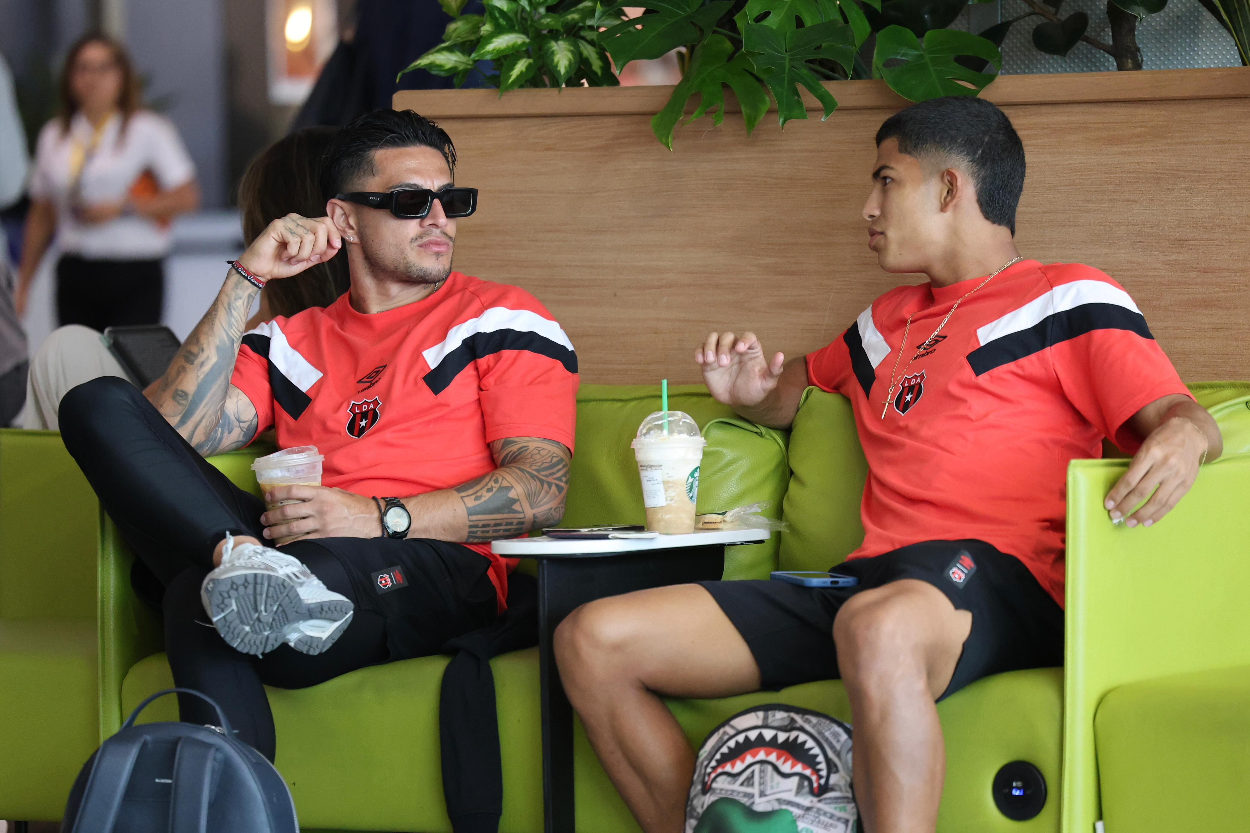 Rónald Matarrita e Isaac Badilla conversan mientras esperaban abordar el vuelo que llegó a Liga Deportiva Alajuelense a El Salvador.
