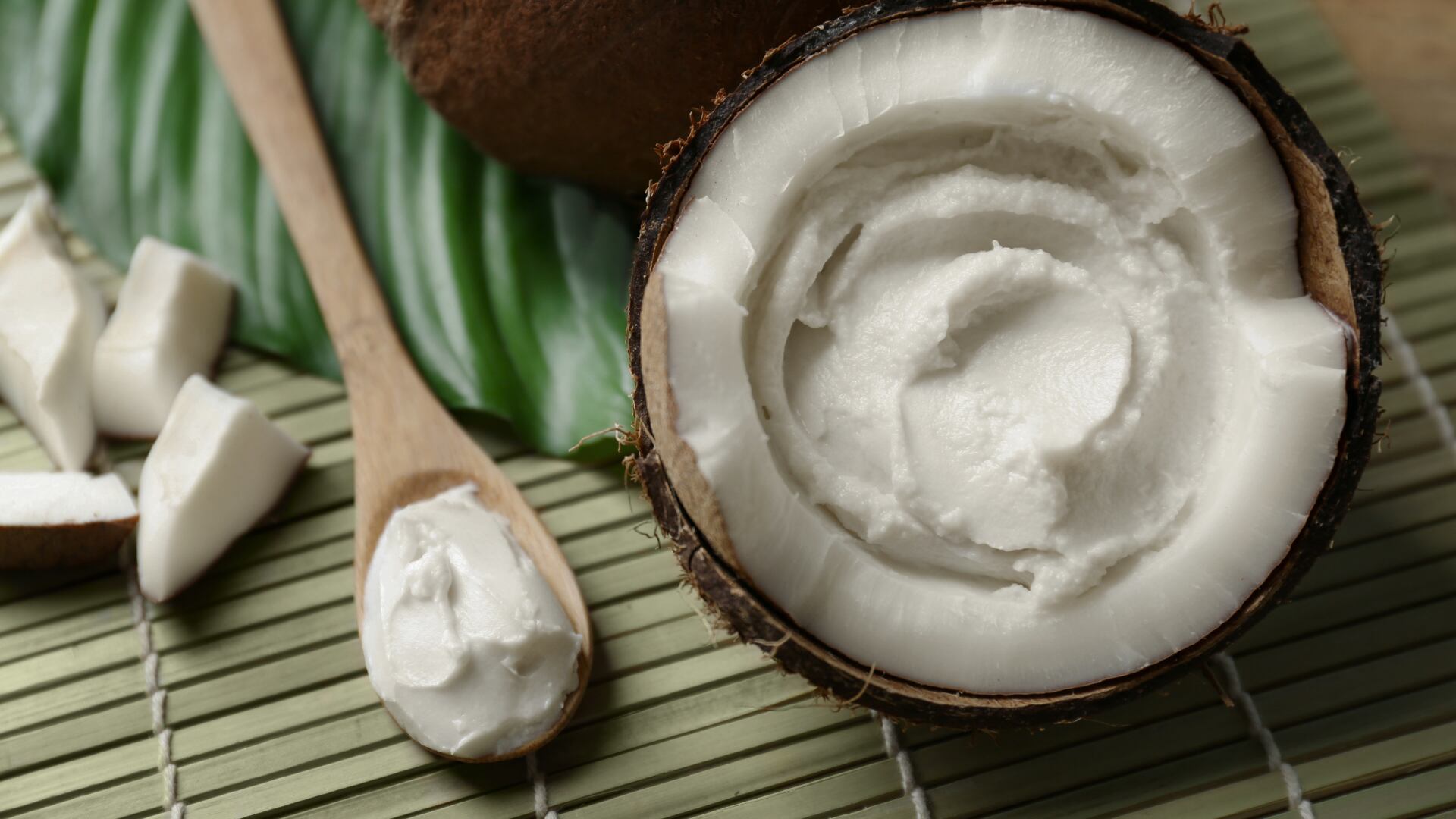 Pulpa de coco fresca sobre una superficie natural, acompañada de una cuchara de madera y trozos de coco, usada como alimento beneficioso para aliviar la gastritis por sus propiedades digestivas y antiinflamatorias.