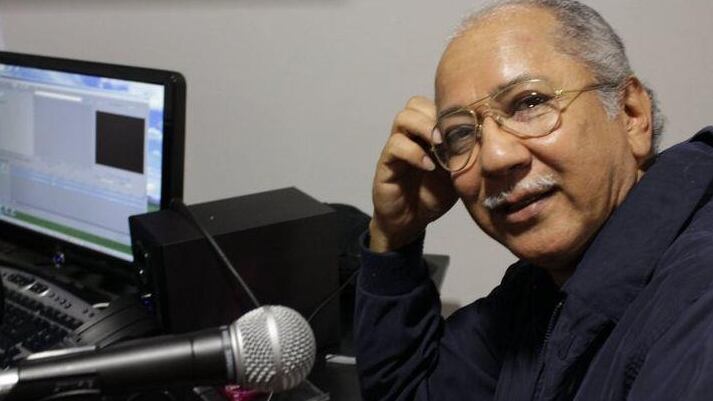 Imagen del músico costarricense Rodolfo Emilio Morales, compositor de éxitos como 'María', en la foto se ve recostado a una mesa y posando junto a un micrófono.